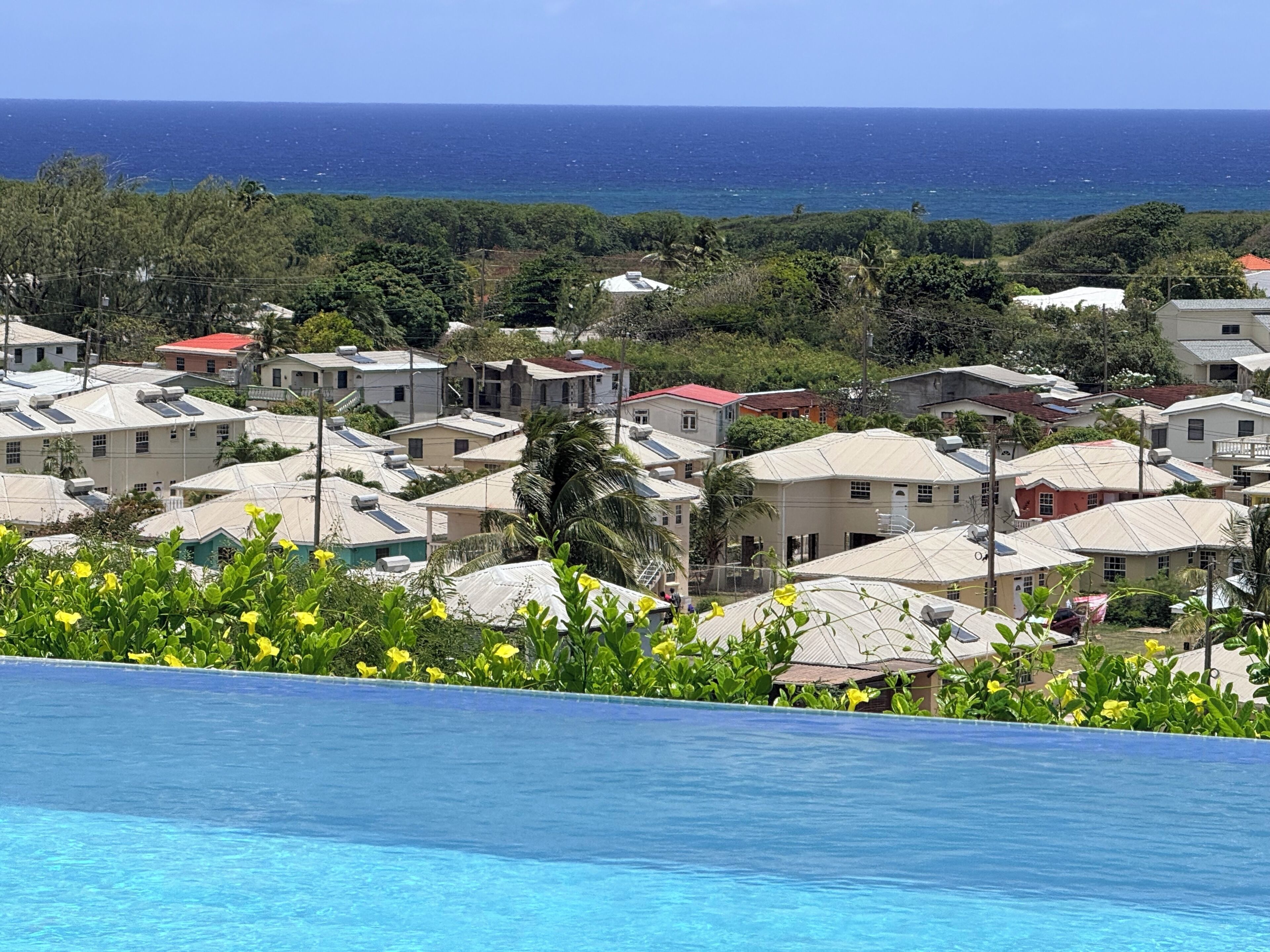 A view over the pool edge of house roofs and the sea.
