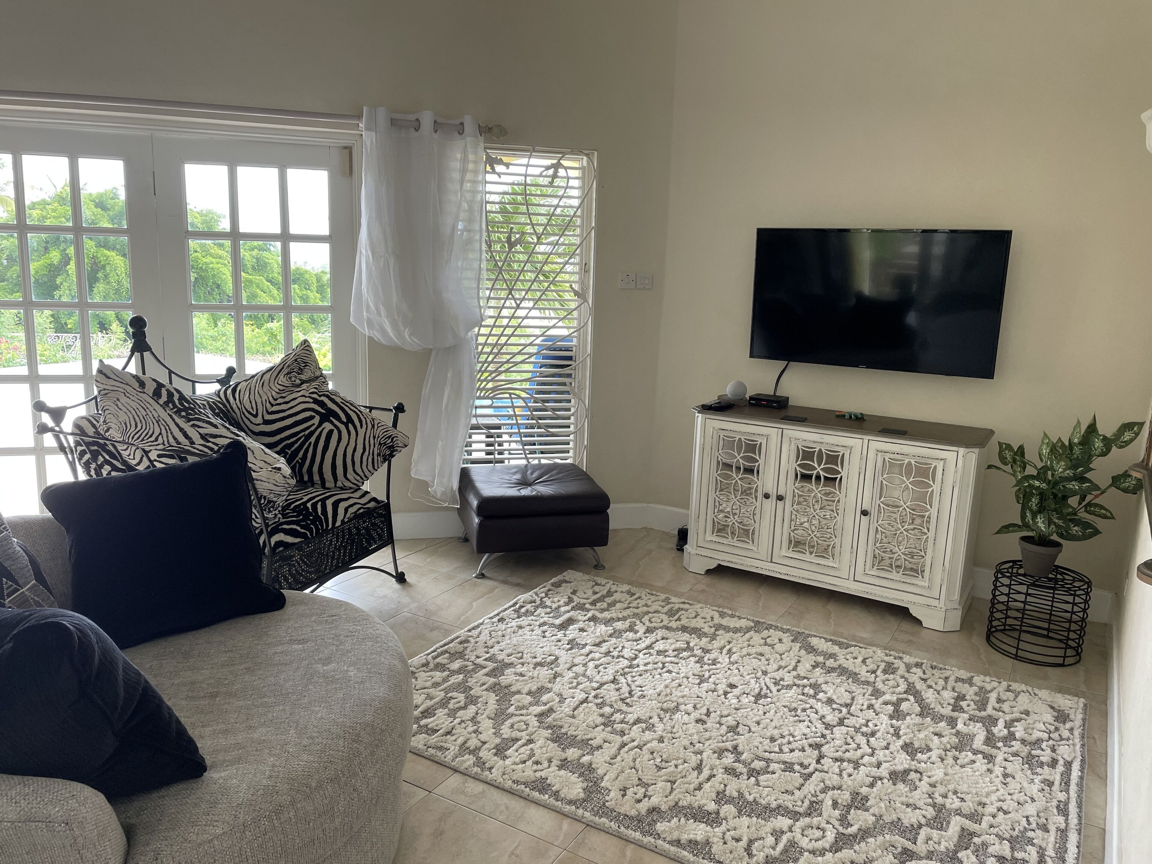 A living room with a sofa, two armchairs, a rug, and a television.
