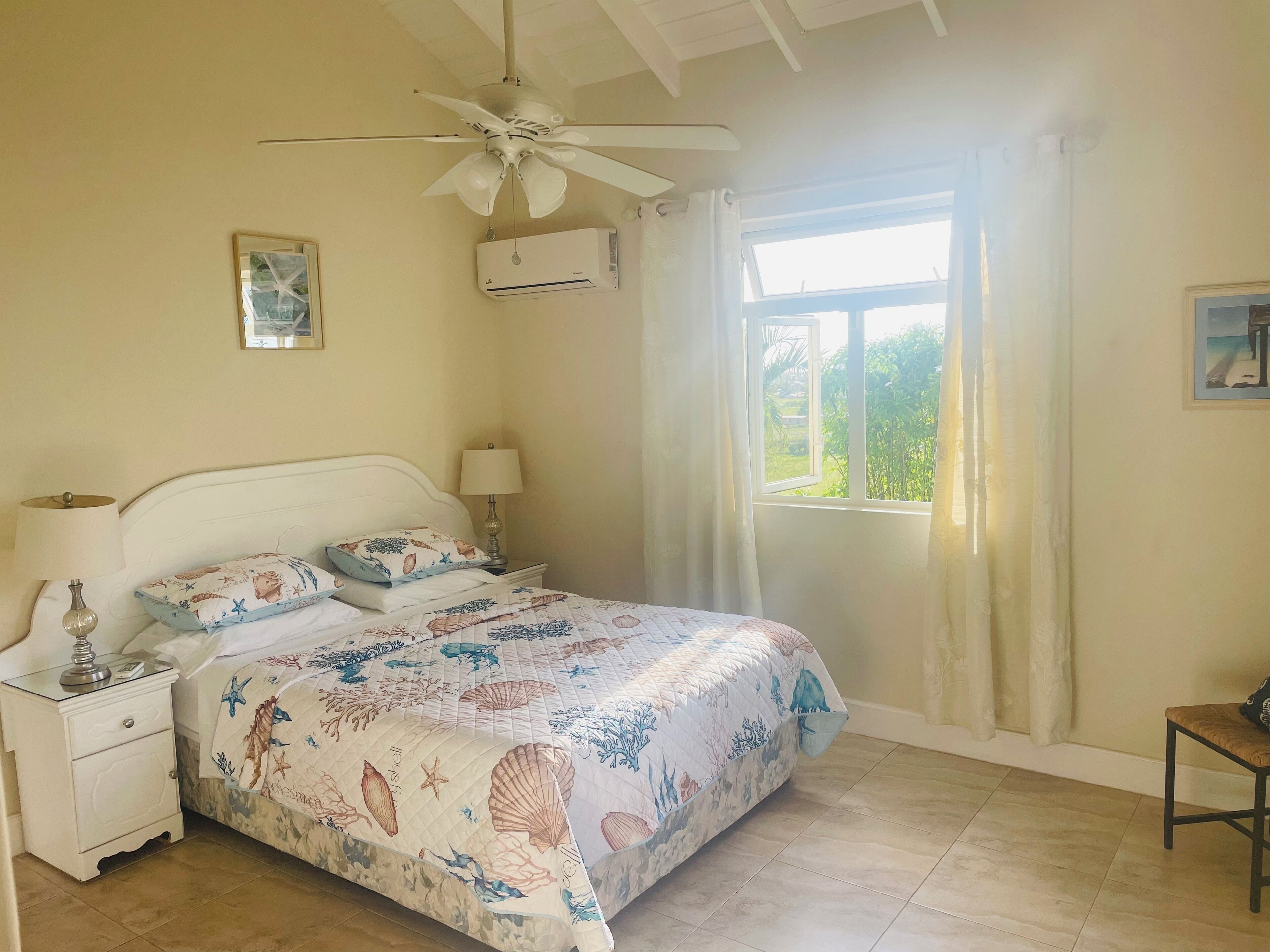 A bedroom with a double bed, a ceiling fan, and an air-conditioning unit.