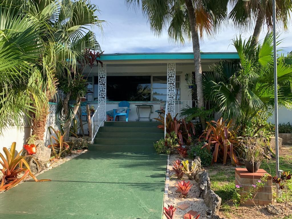 The front porch of the house with palm trees.