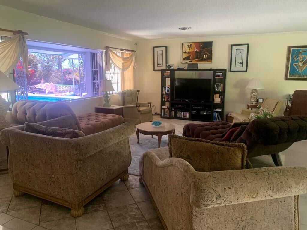 A living room with a view of the pool through a large window.