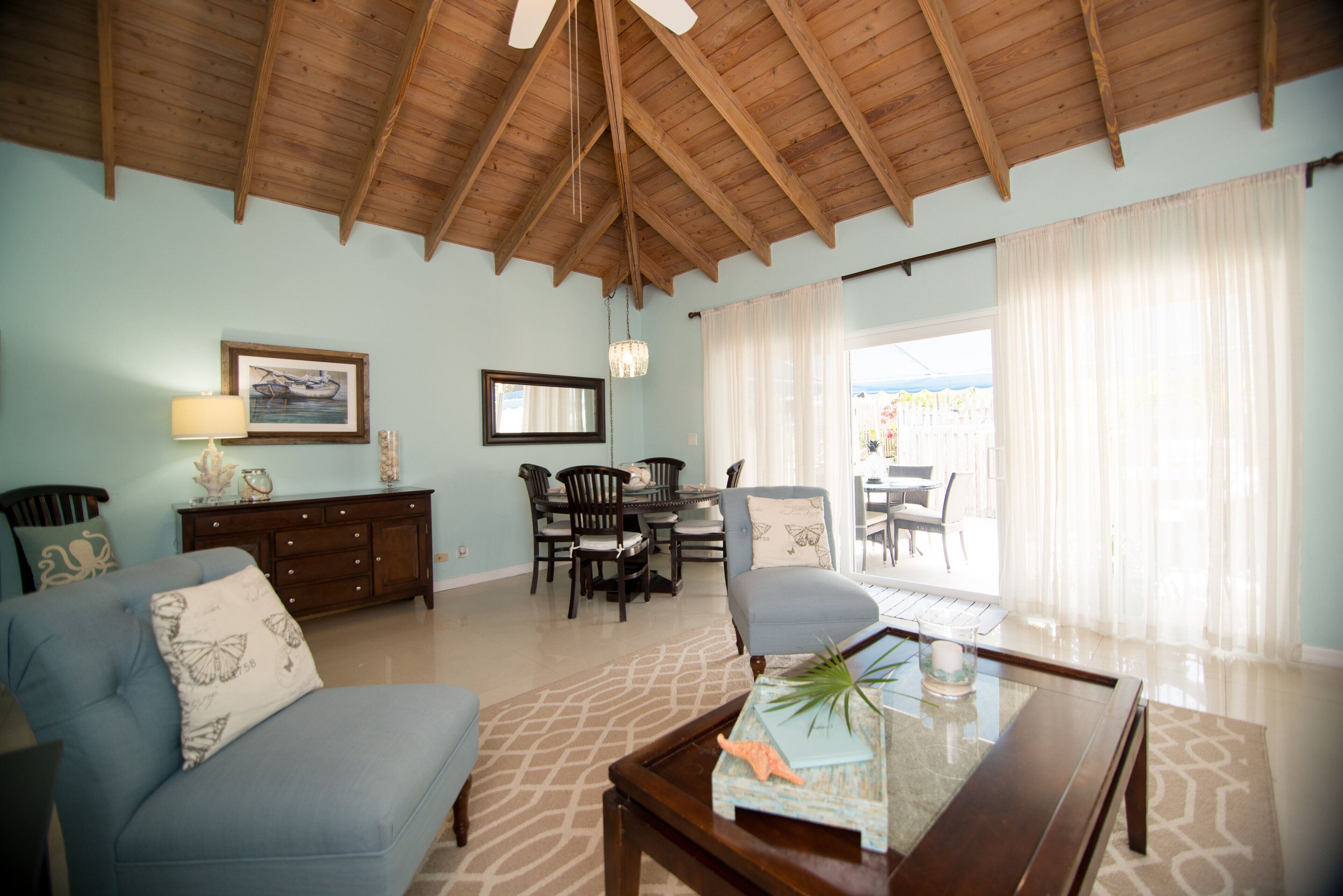 The living room and the dining area, with a wood ceiling and a door to the patio.