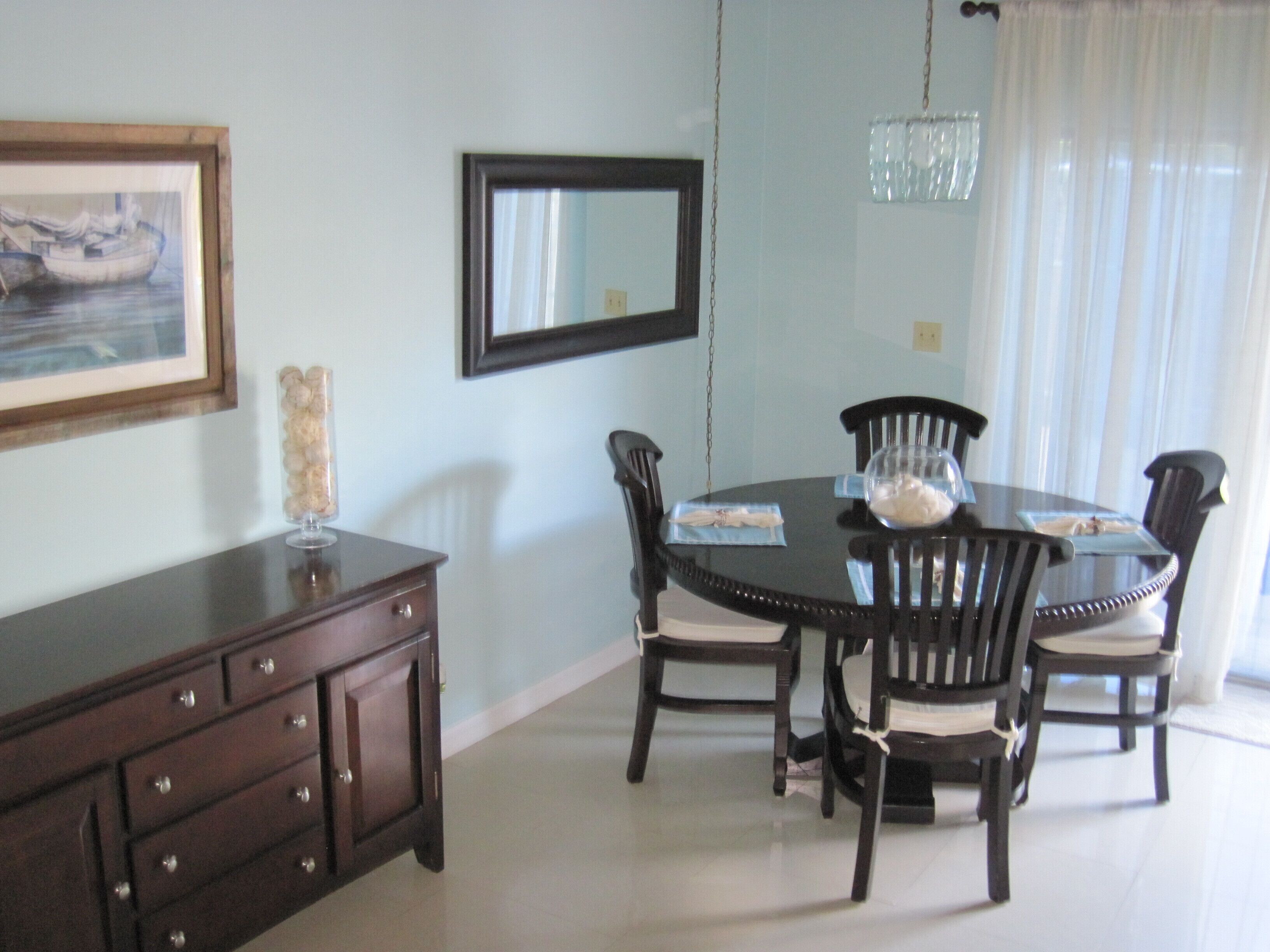 The dining table with four chairs next to a sideboard.