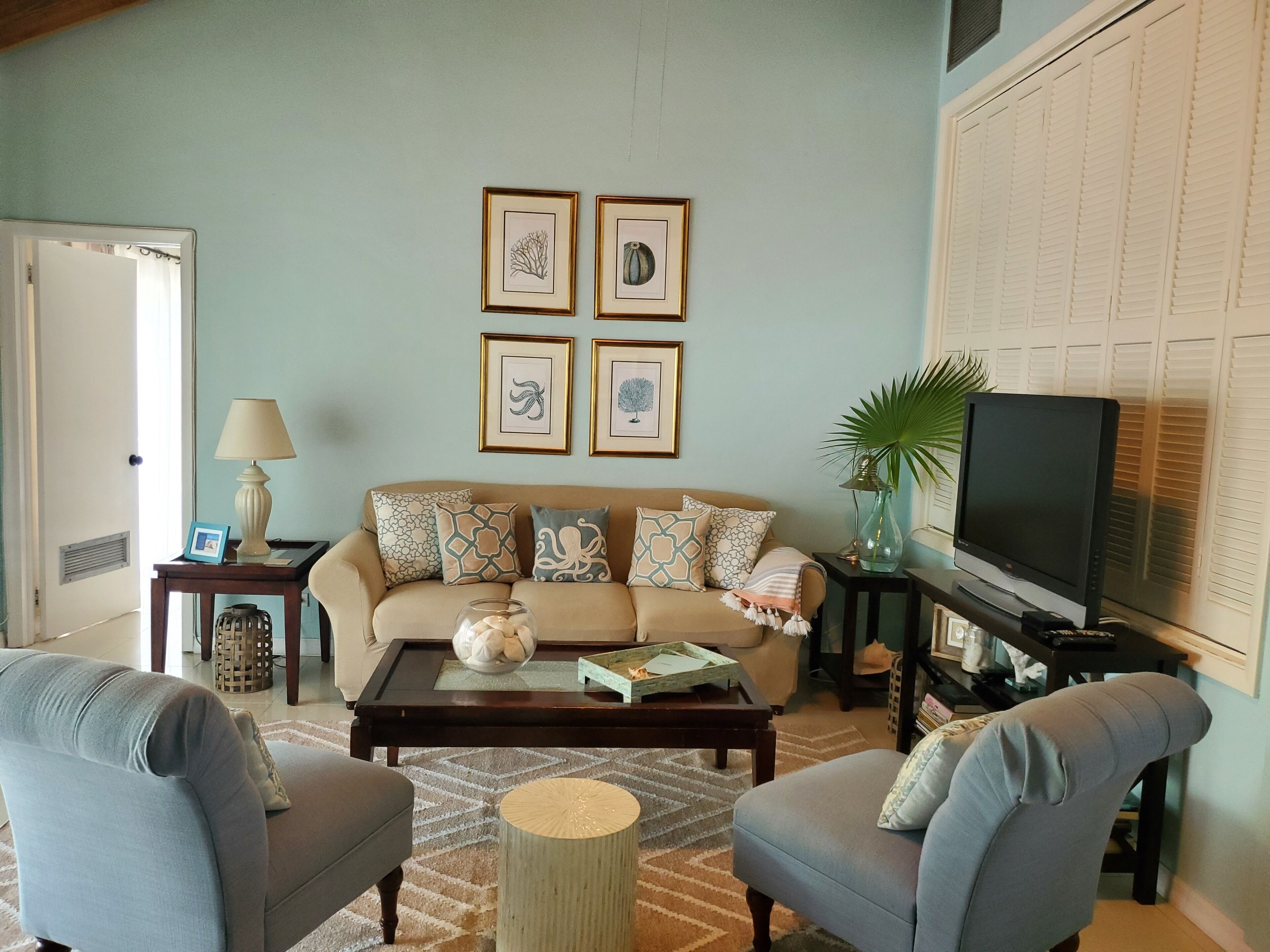 The living room with a sofa, a television, and white shutters.