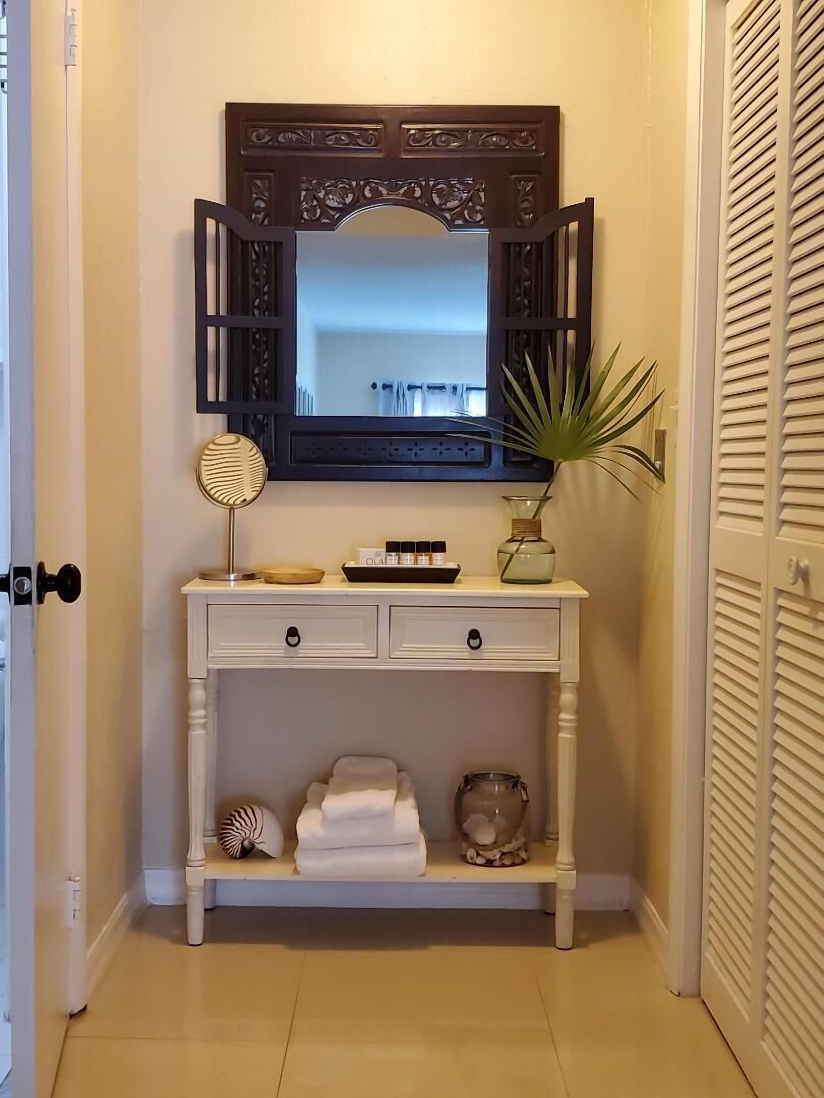 A hallway table with towels, a mirror, and toiletries.