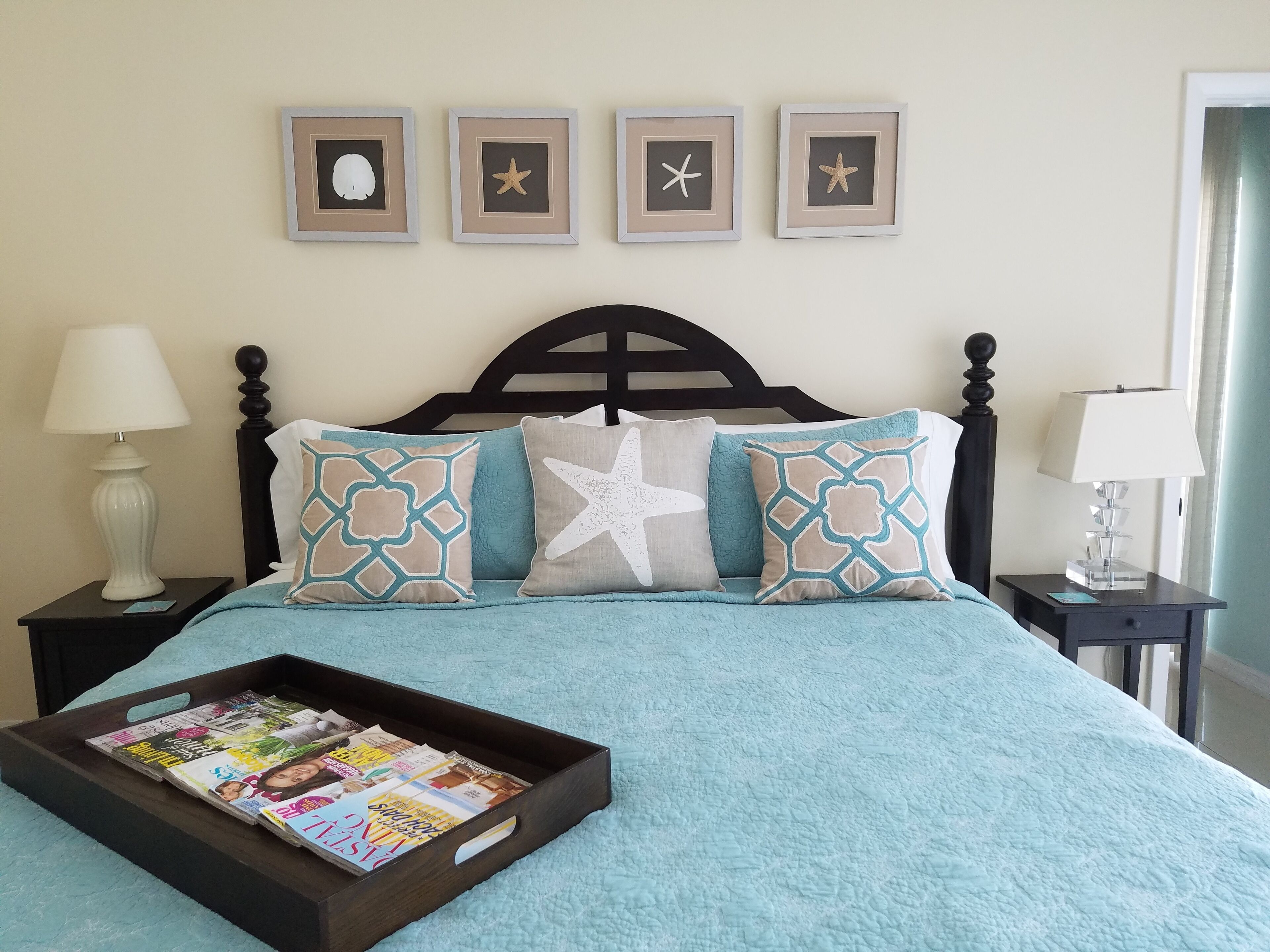 A bed with a turquoise bedspread and a starfish pillow.