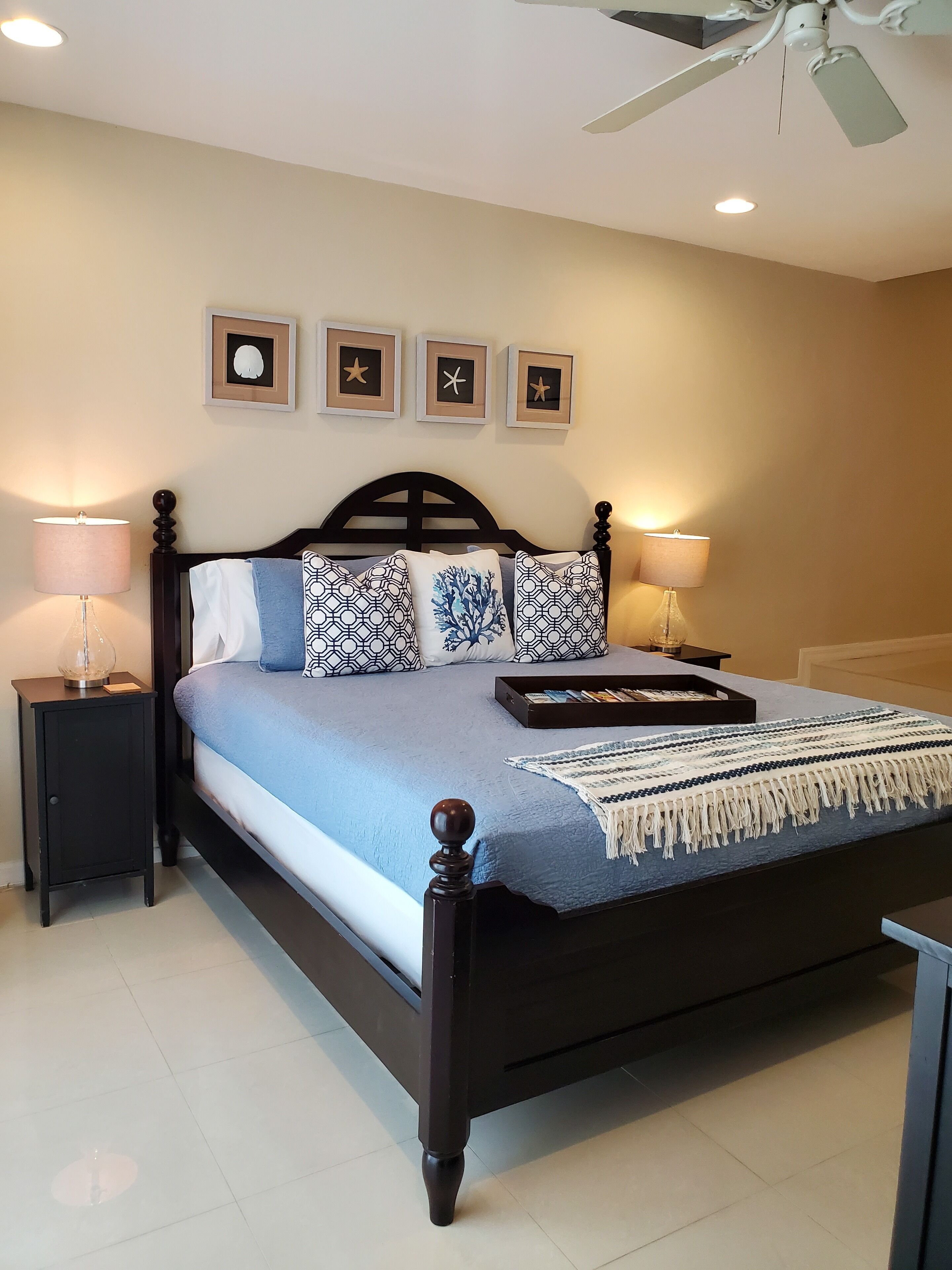 A bedroom with a blue bedspread and a ceiling fan.