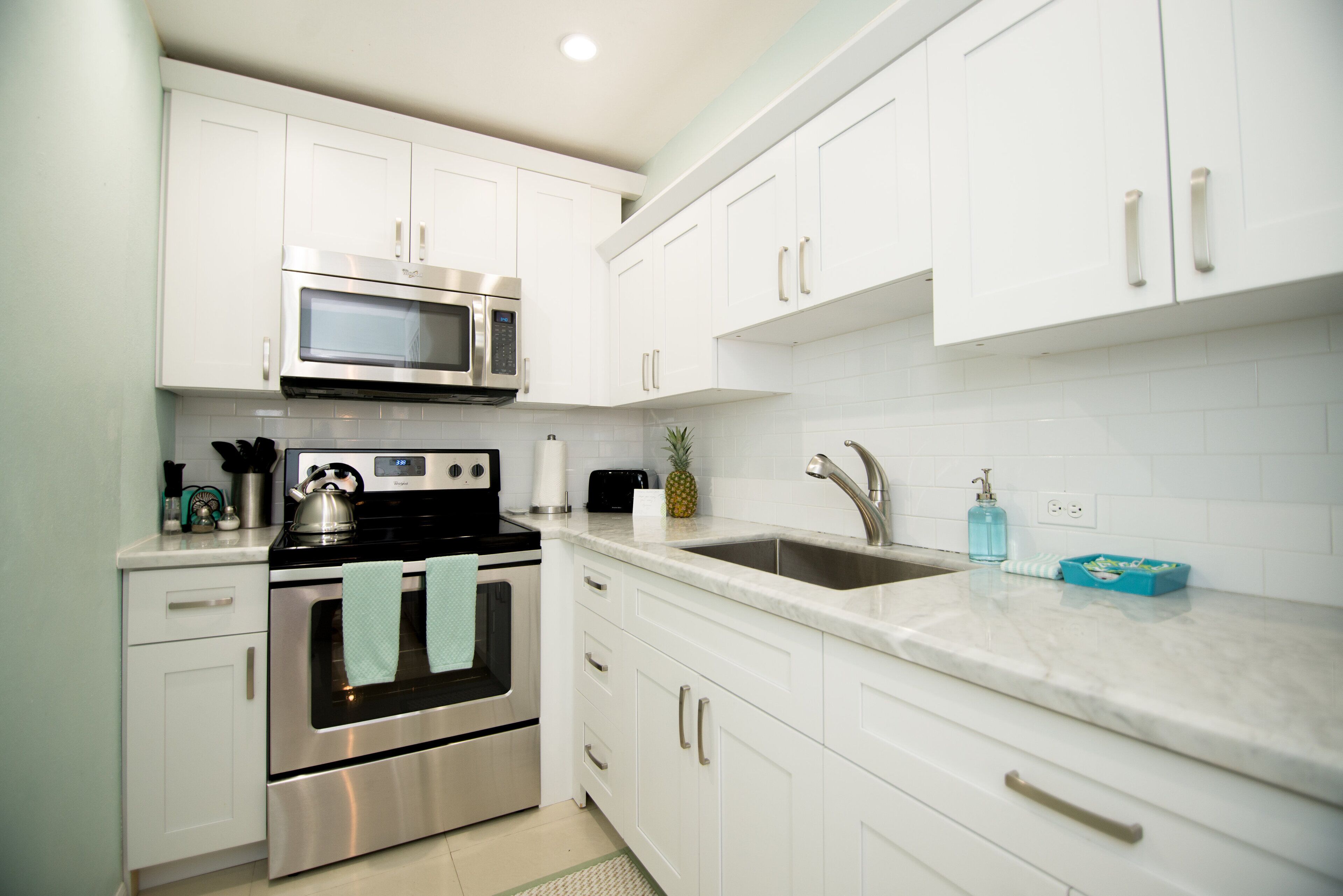 The kitchen with white cabinets and a large sink.