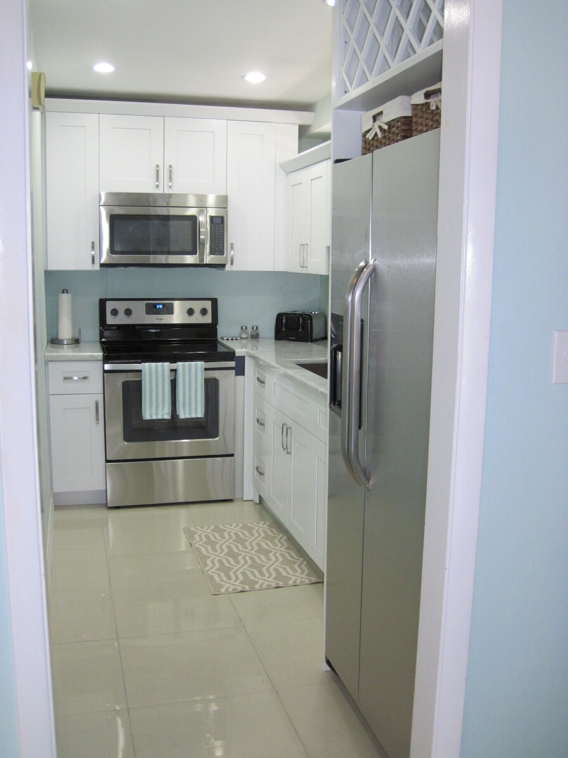 The kitchen with a stainless steel refrigerator, seen from the doorway.