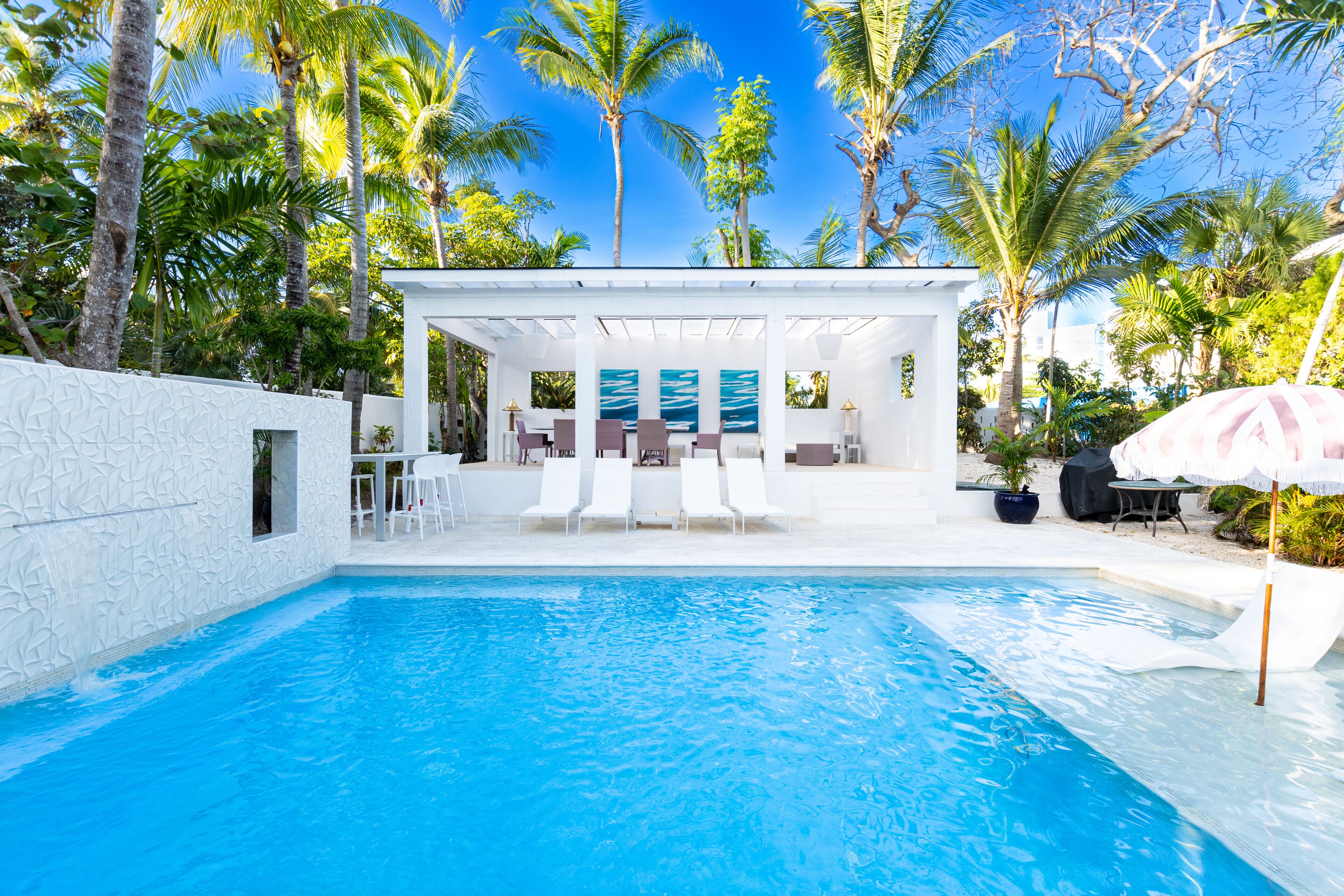 The pool and the white cabana with a dining table.