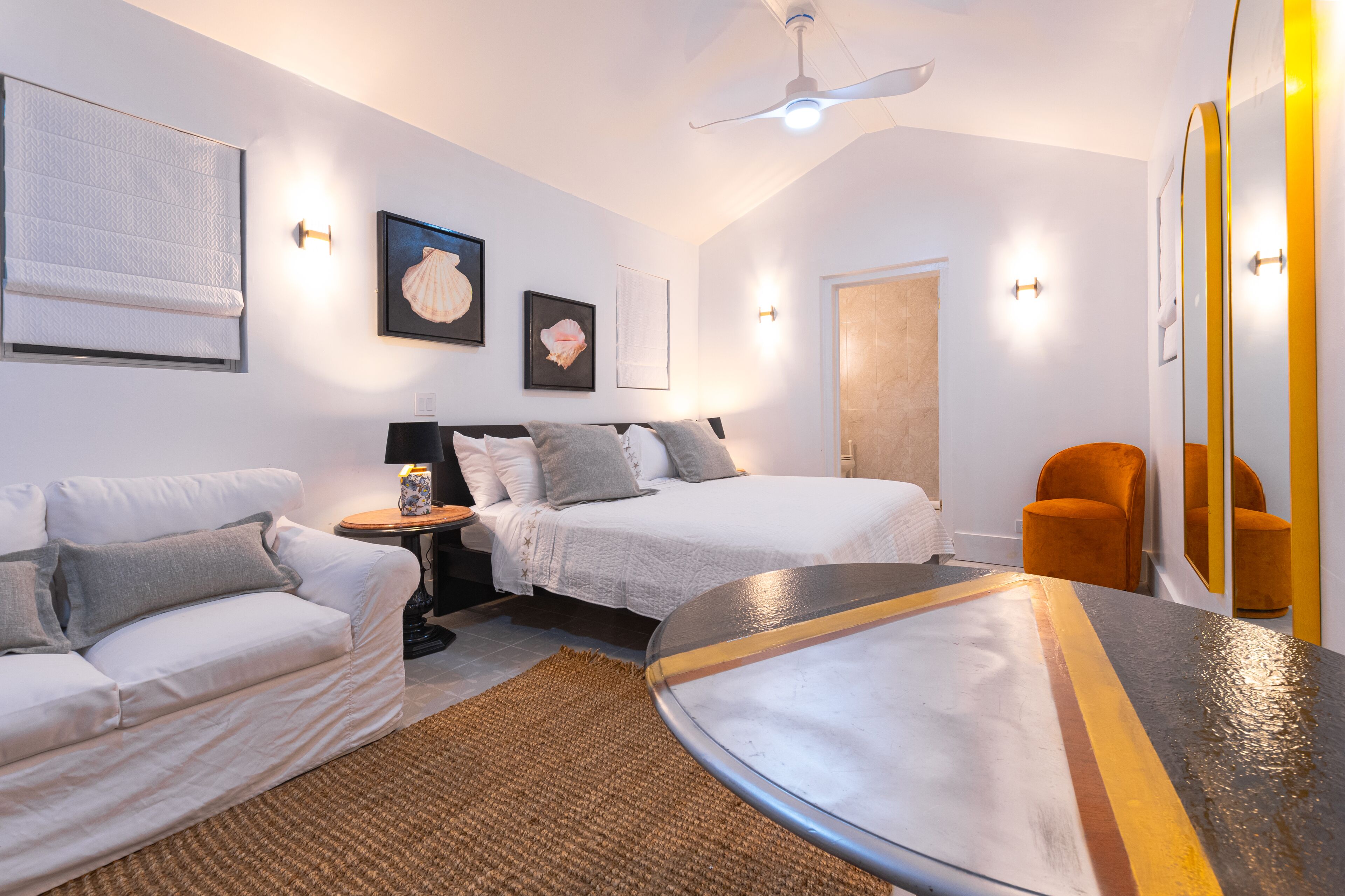 A bedroom with pink pillows, two lamps, and two cane chairs.