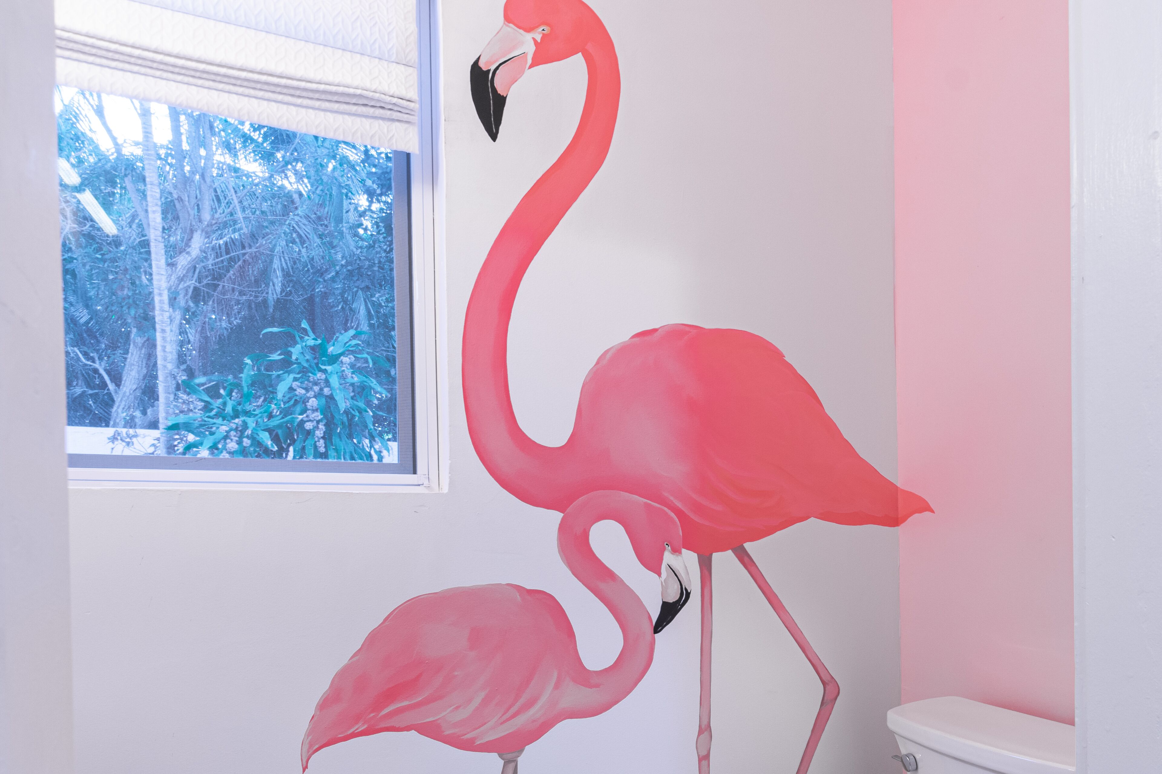 A wall painting of two flamingos in the bathroom.