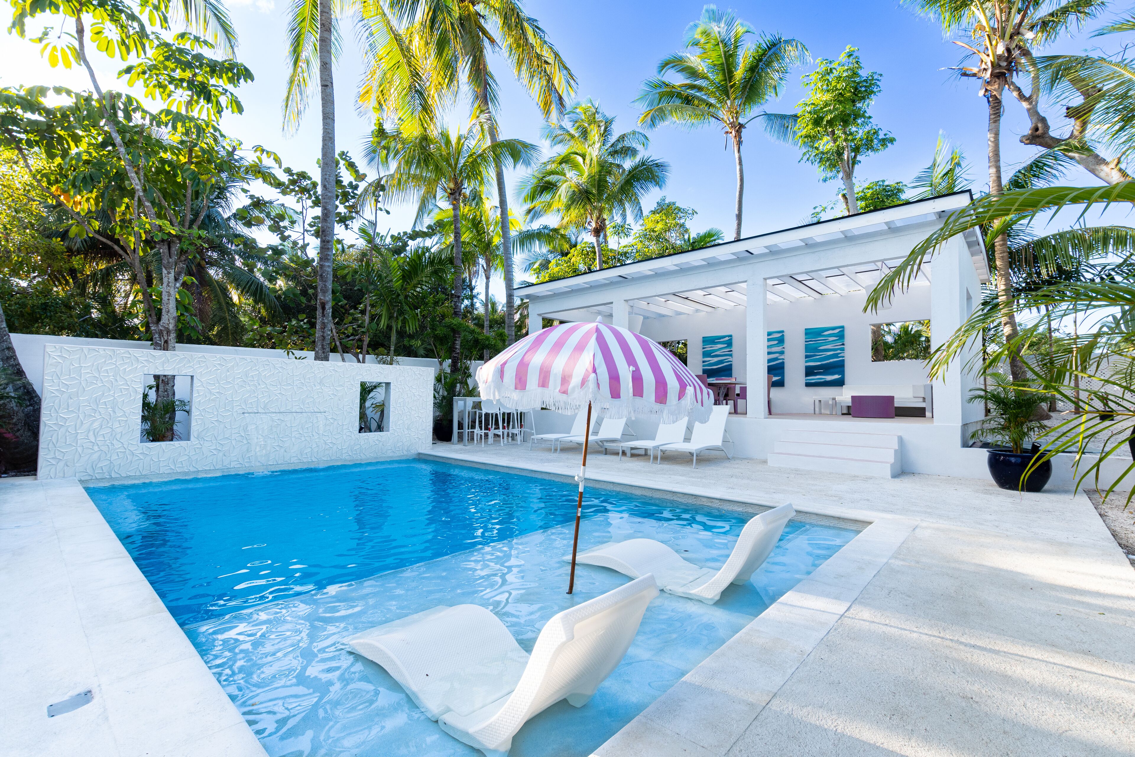 The pool with two sun loungers in the water and the cabana behind.