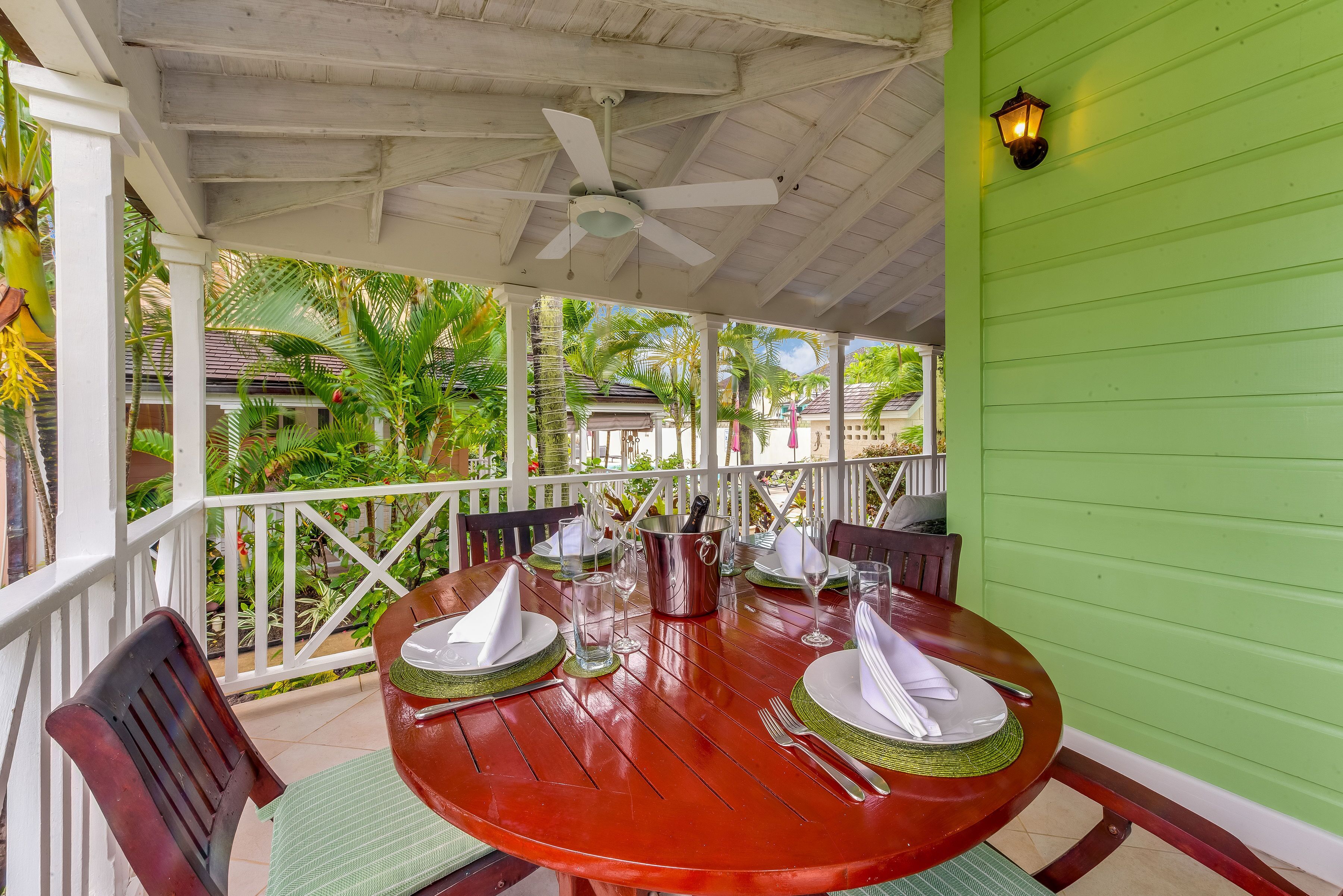 A veranda with an oval wood table and a ceiling fan.
