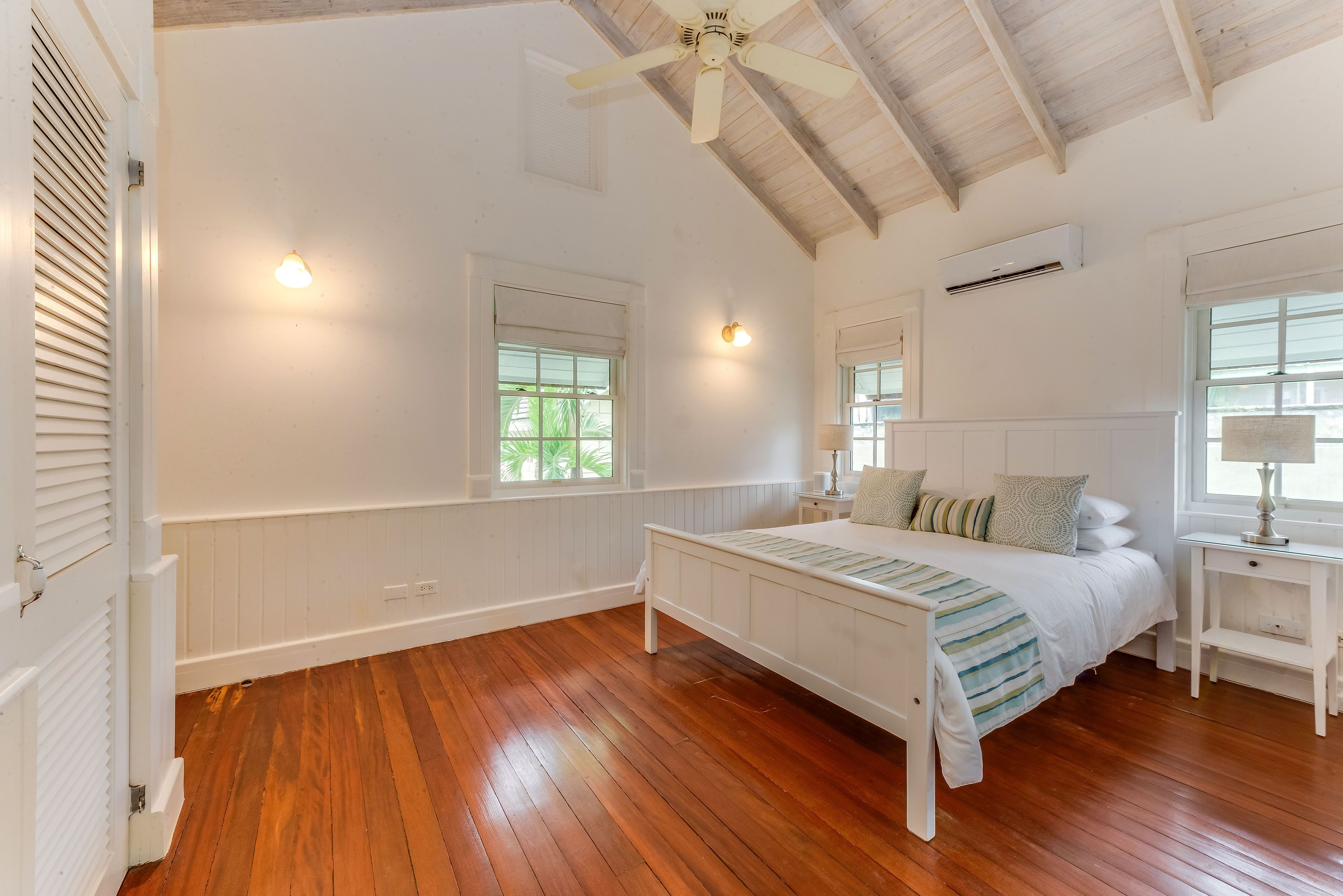 A bedroom with a white bed frame and two windows.