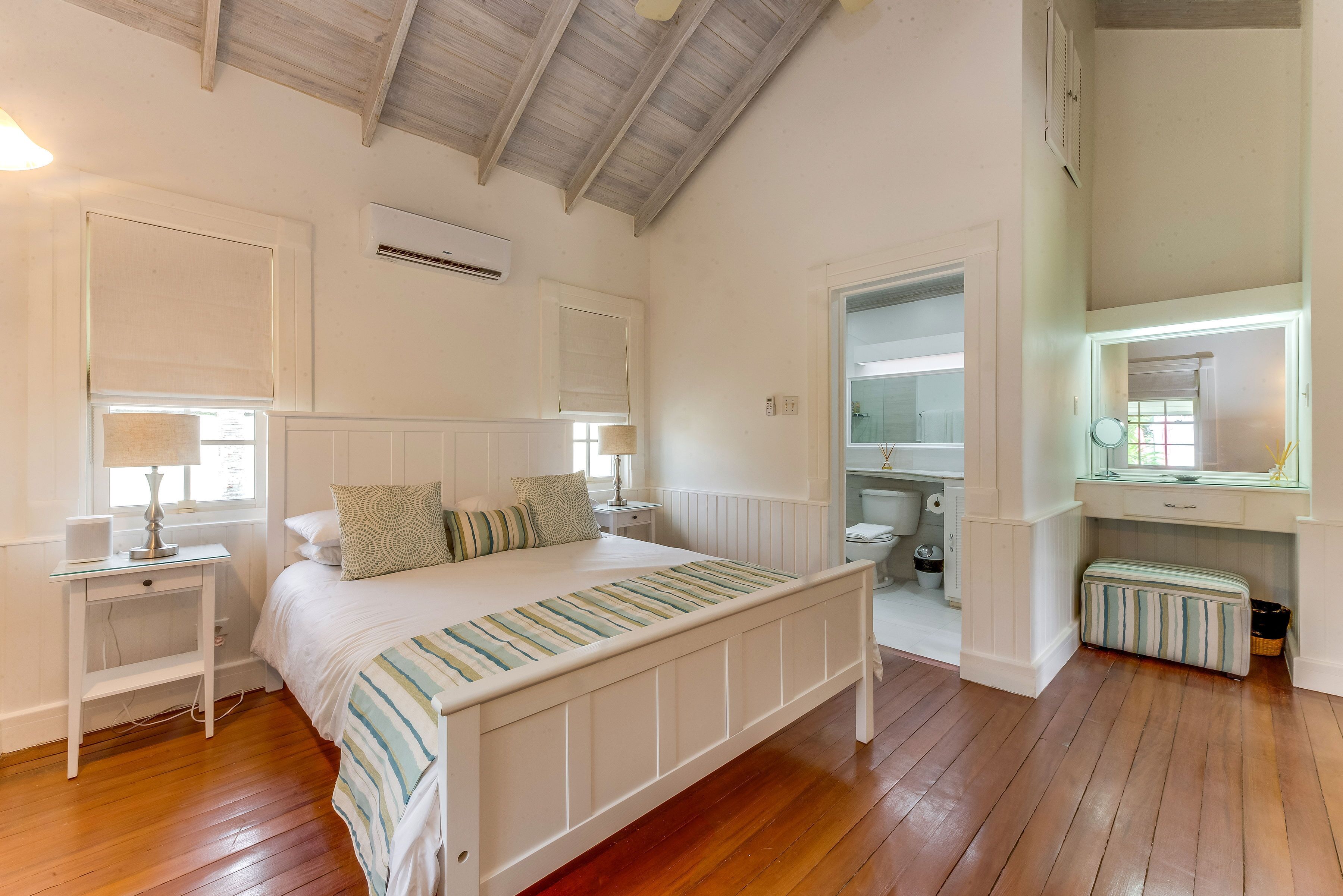 A bedroom with a white bed and a door to the bathroom.