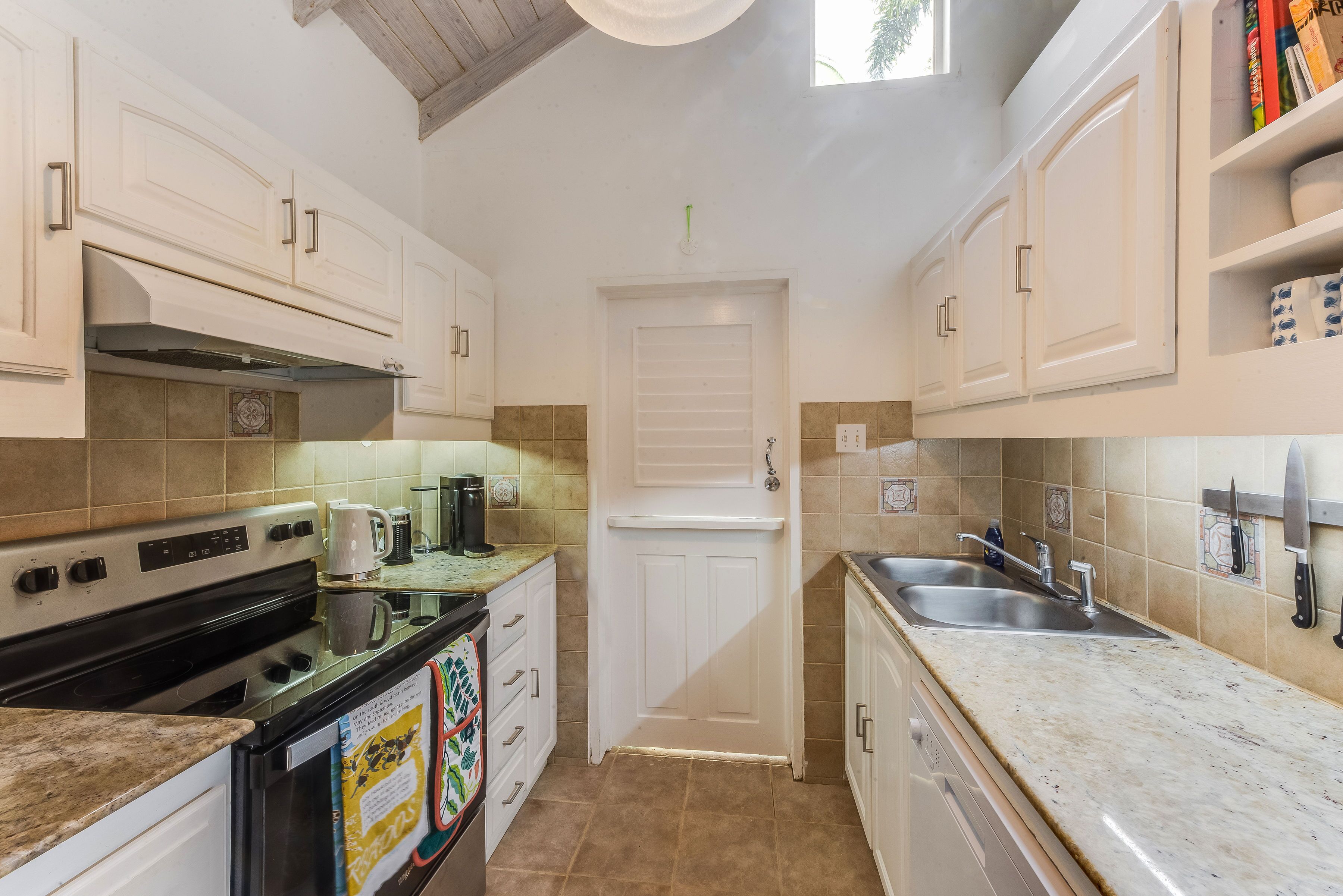 A galley kitchen with white cabinets and a double sink.