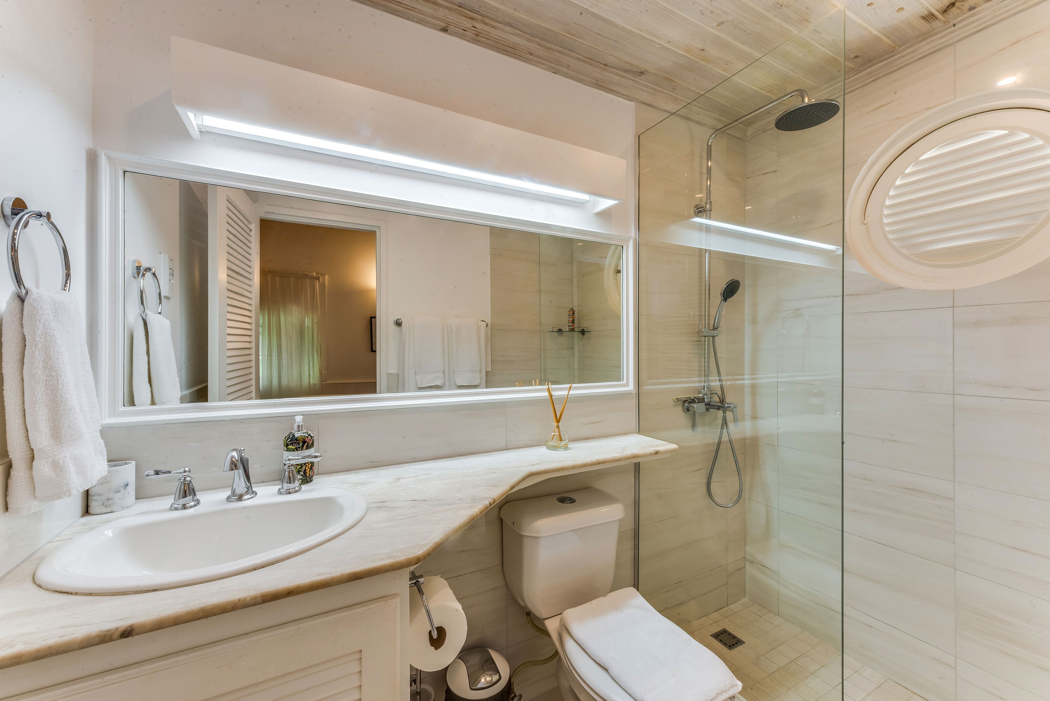 A bathroom with a long mirror and a walk-in shower.