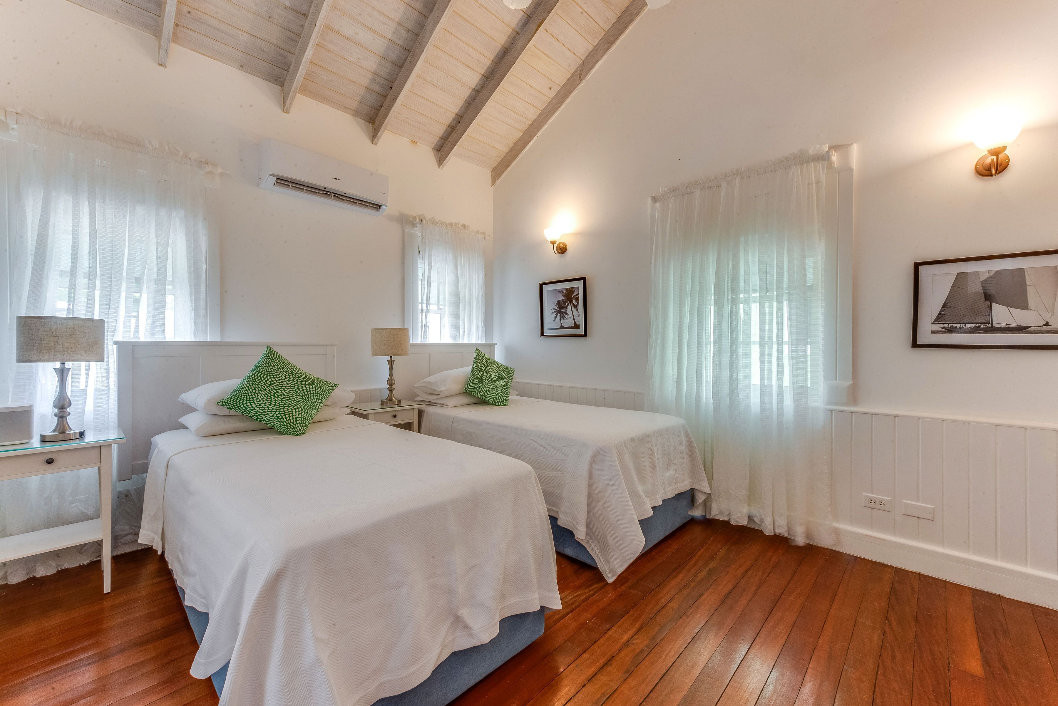 A bedroom with two single beds and green cushions.