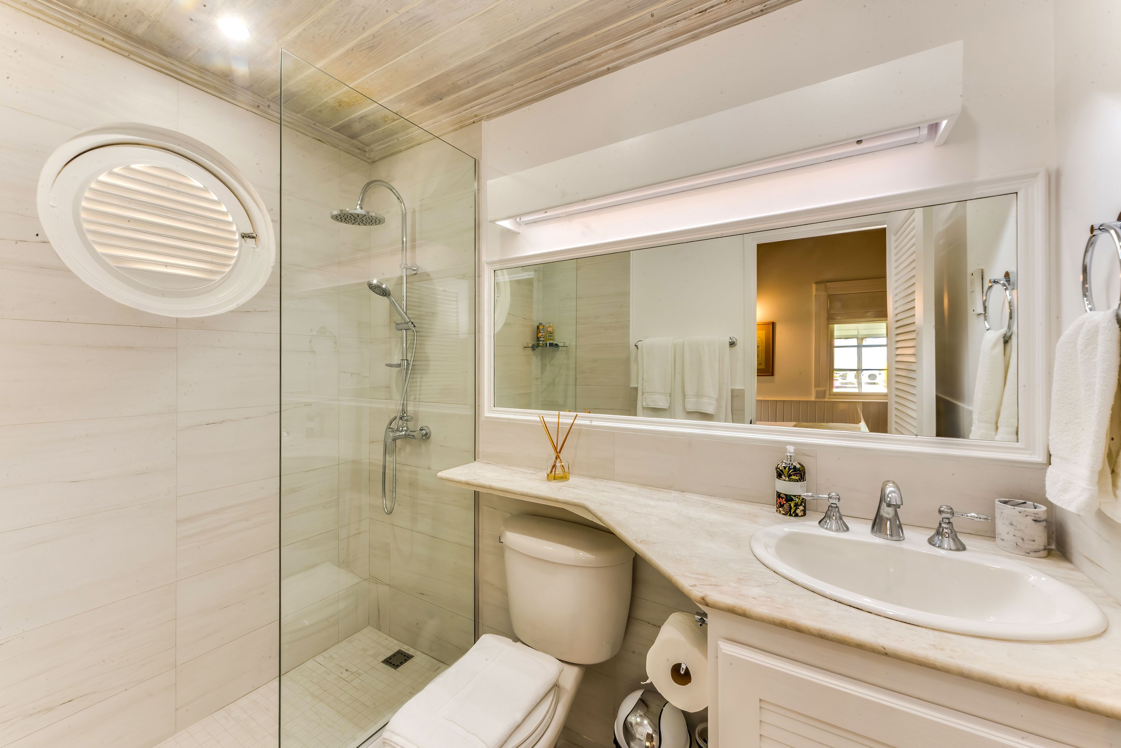 A bathroom with a rain shower behind a glass panel.