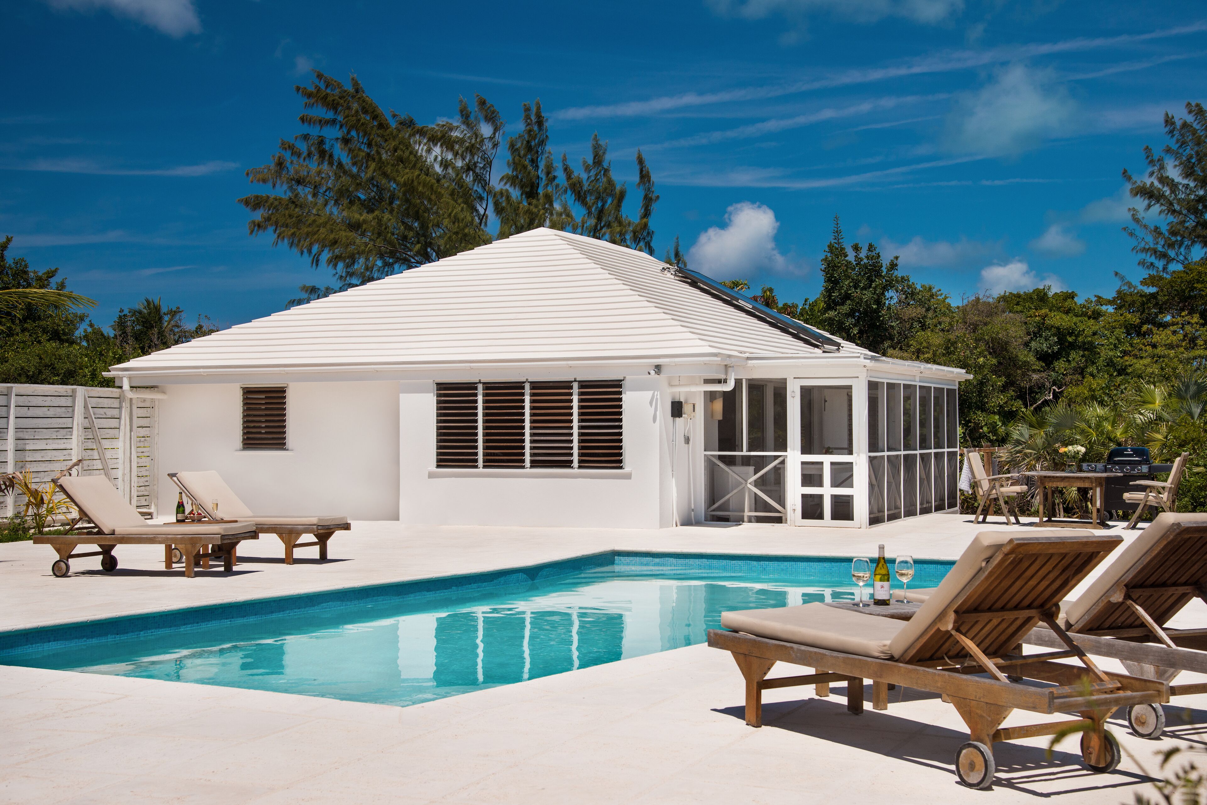 The pool, the loungers, and the villa.