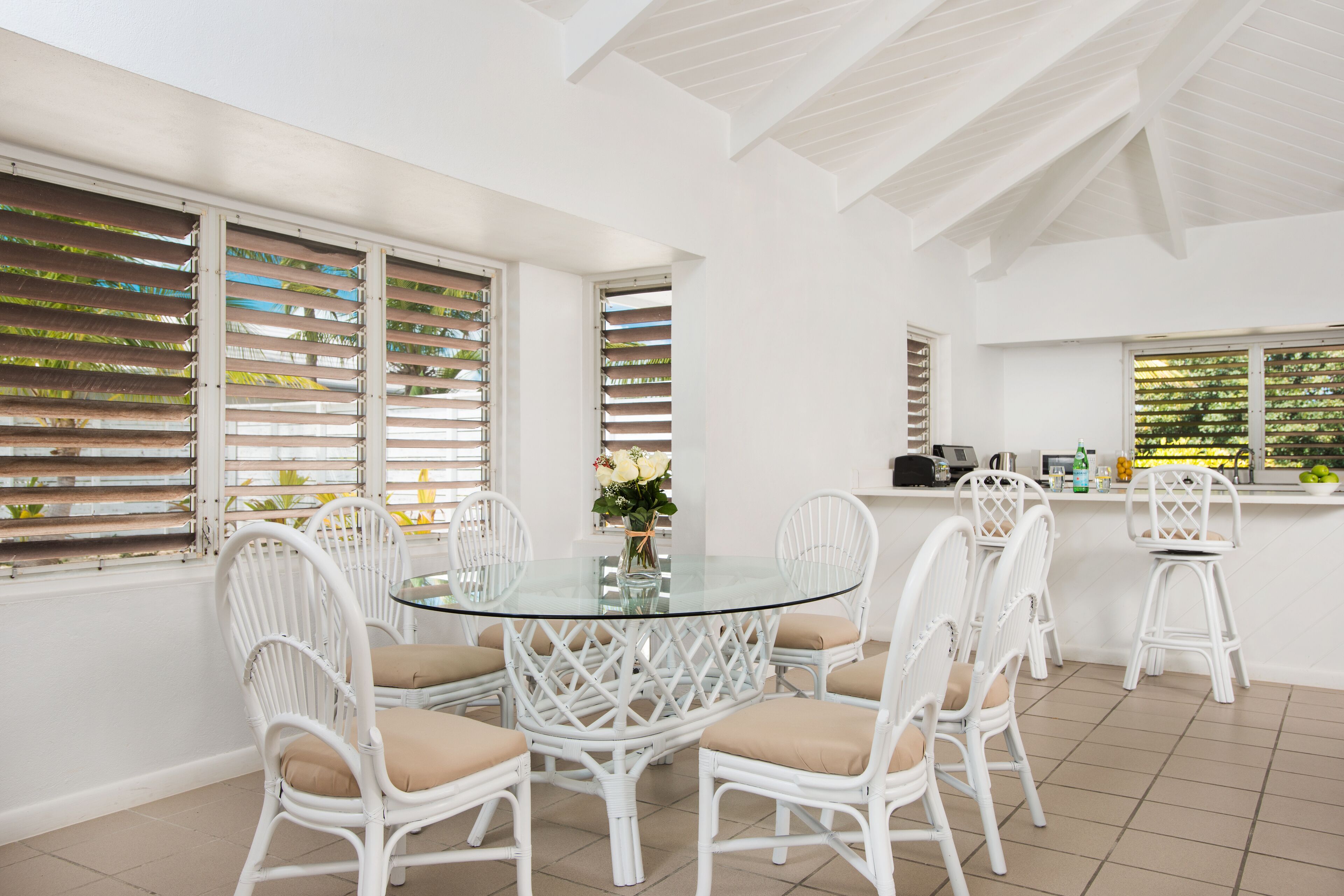 A round glass table with white chairs.