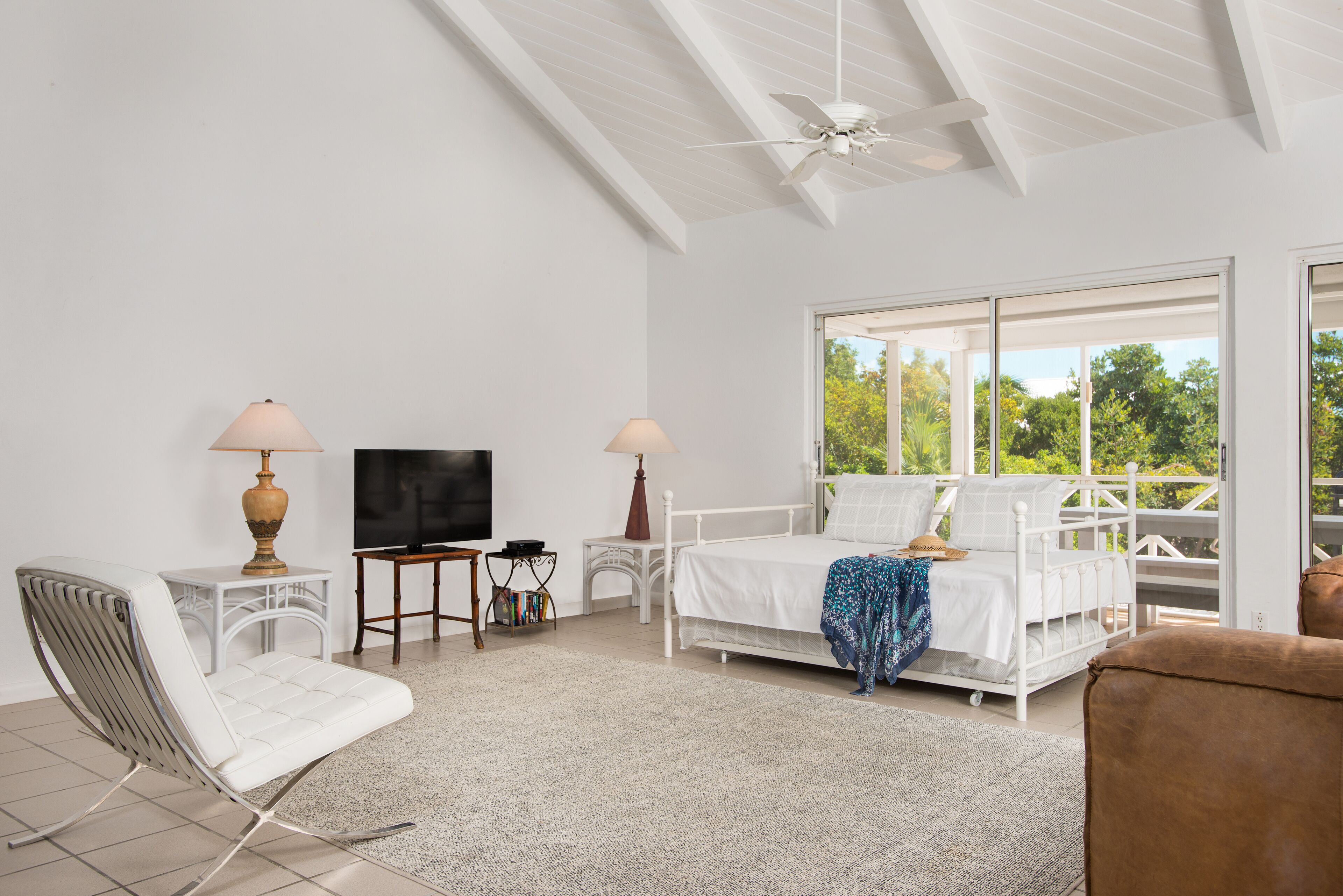 A room with a daybed, a television, and a chair.
