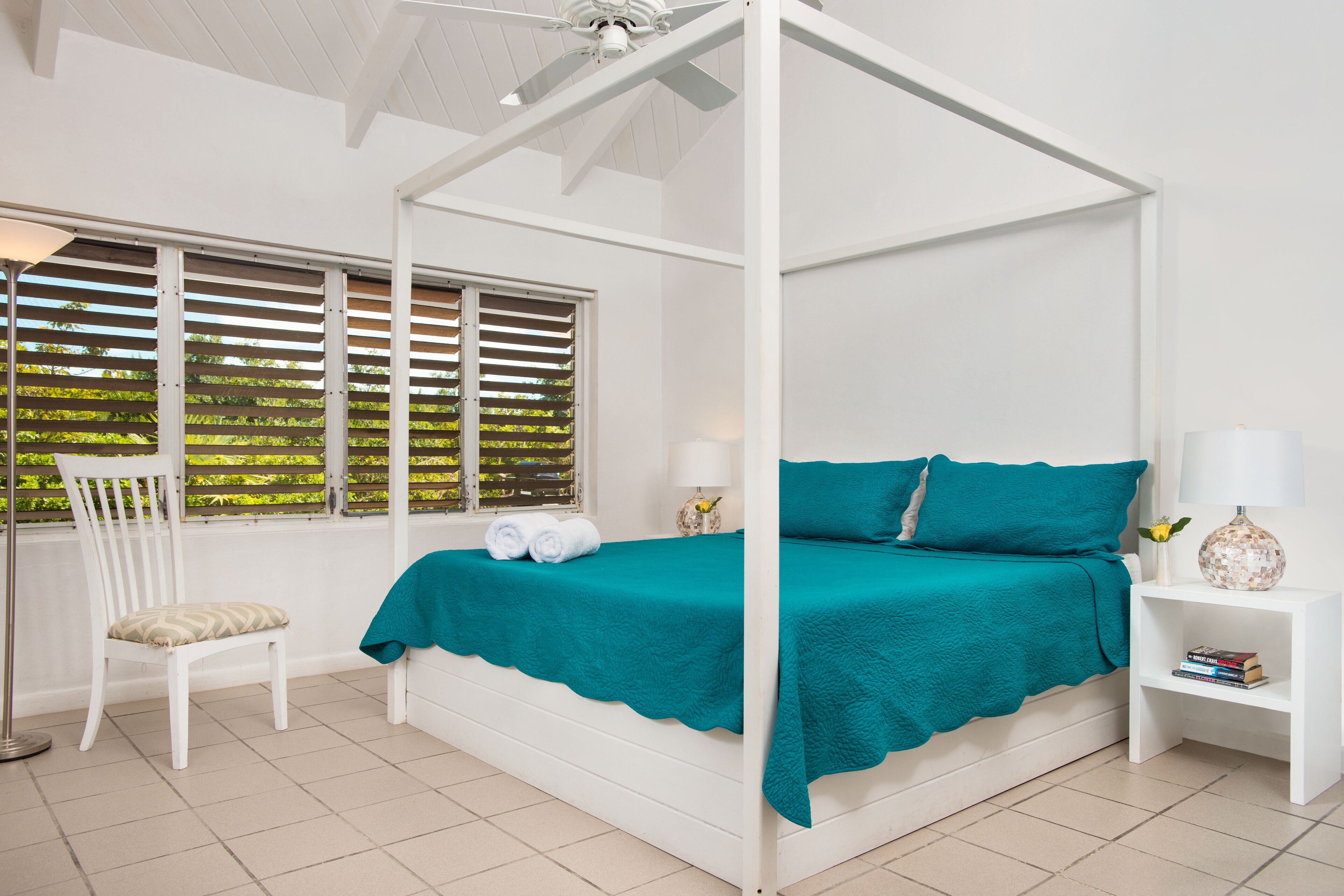 A four-poster bed with a teal cover.