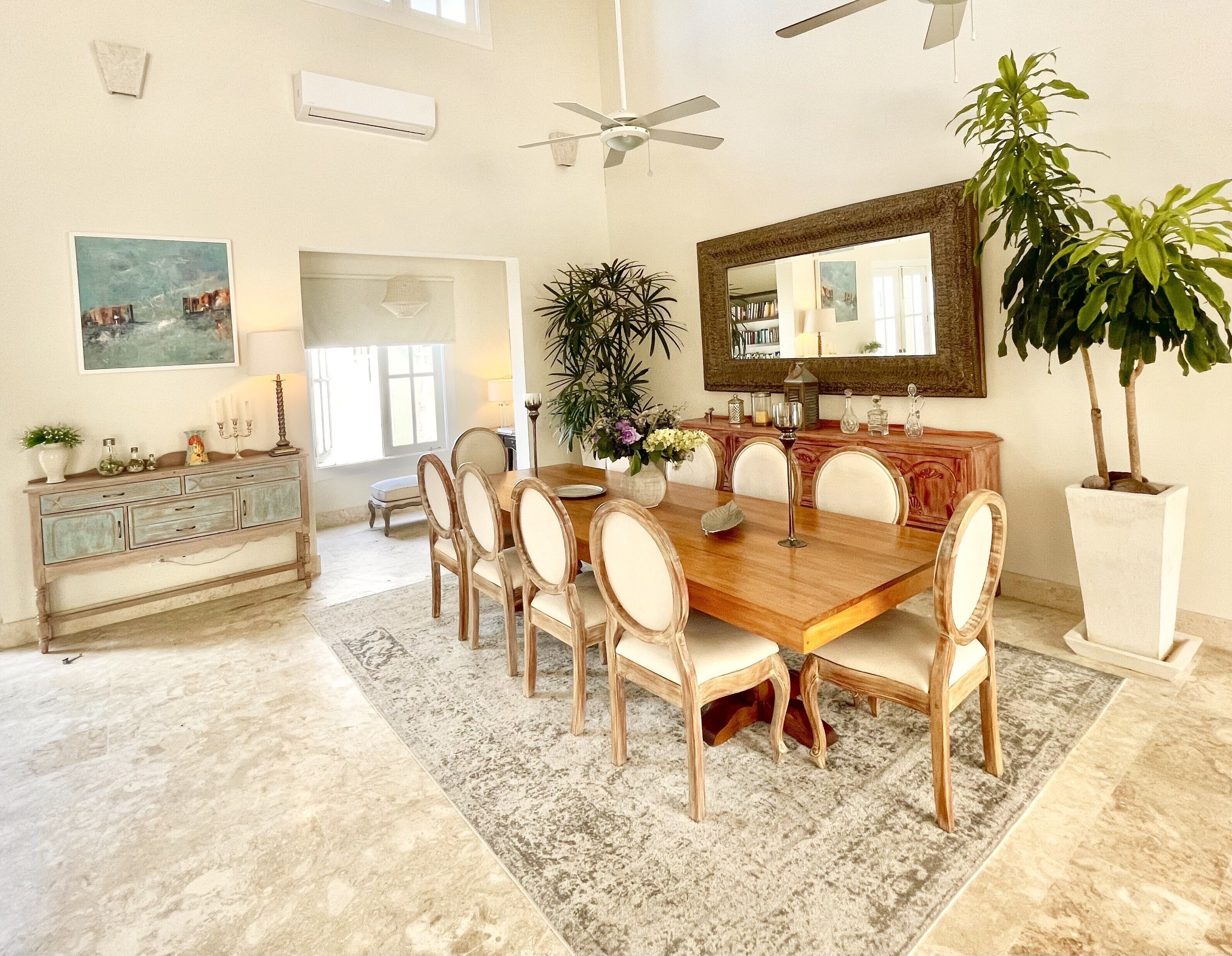 A dining room with a wooden table, upholstered chairs, and a large mirror.