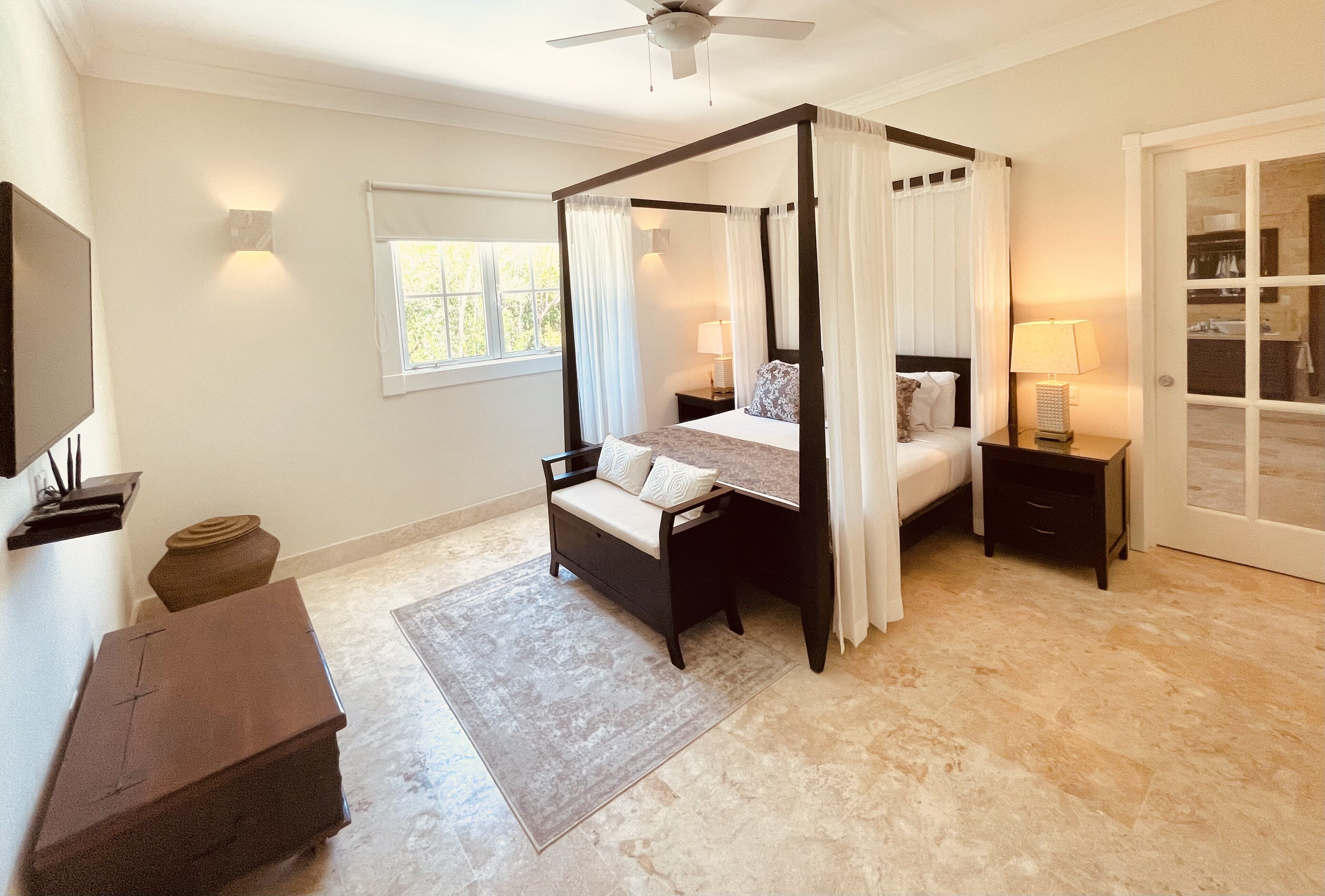 A bedroom with a four-poster bed, two nightstands, and a television.