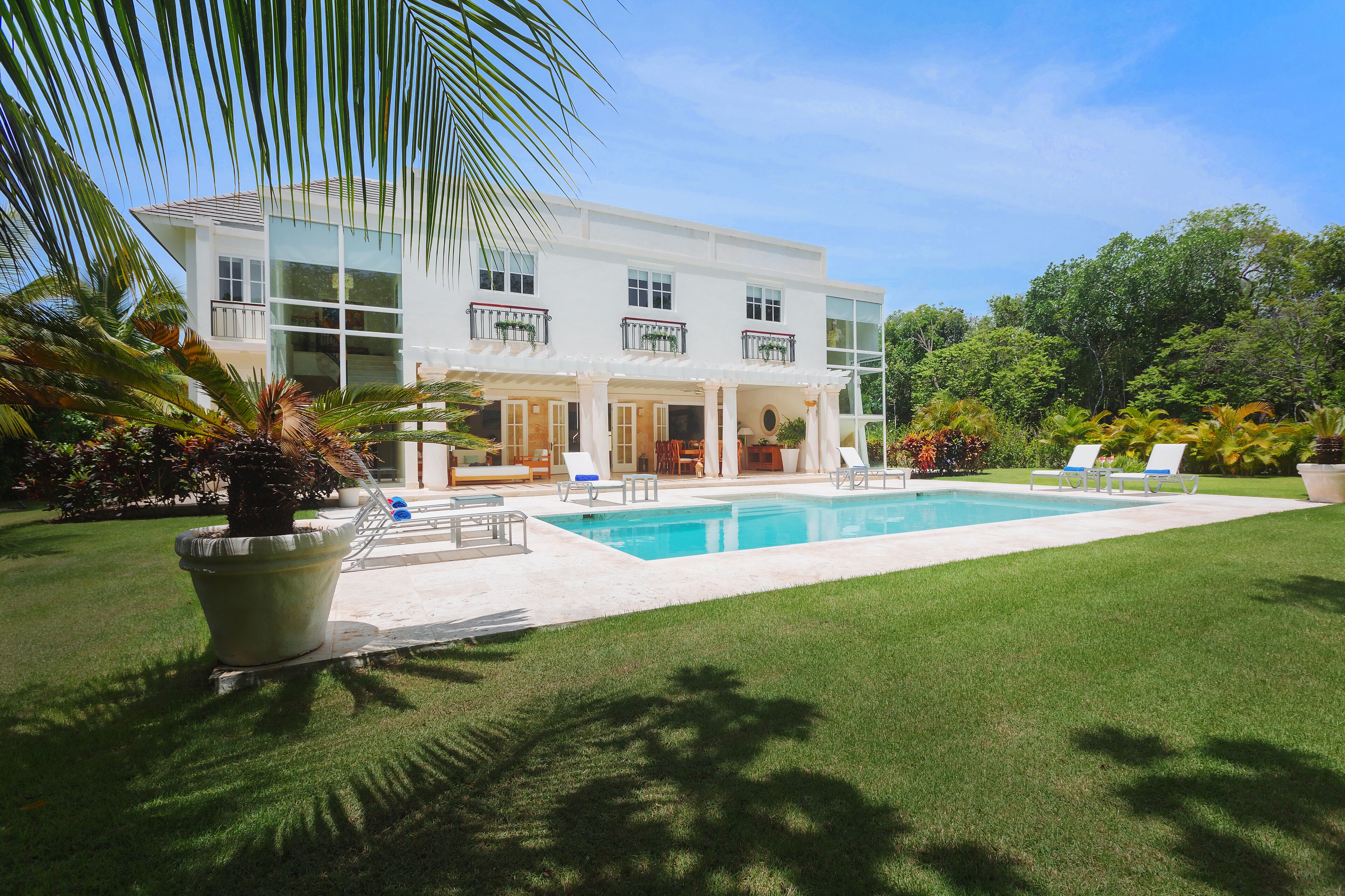 The villa exterior with the private pool, sun loungers, and the lawn.