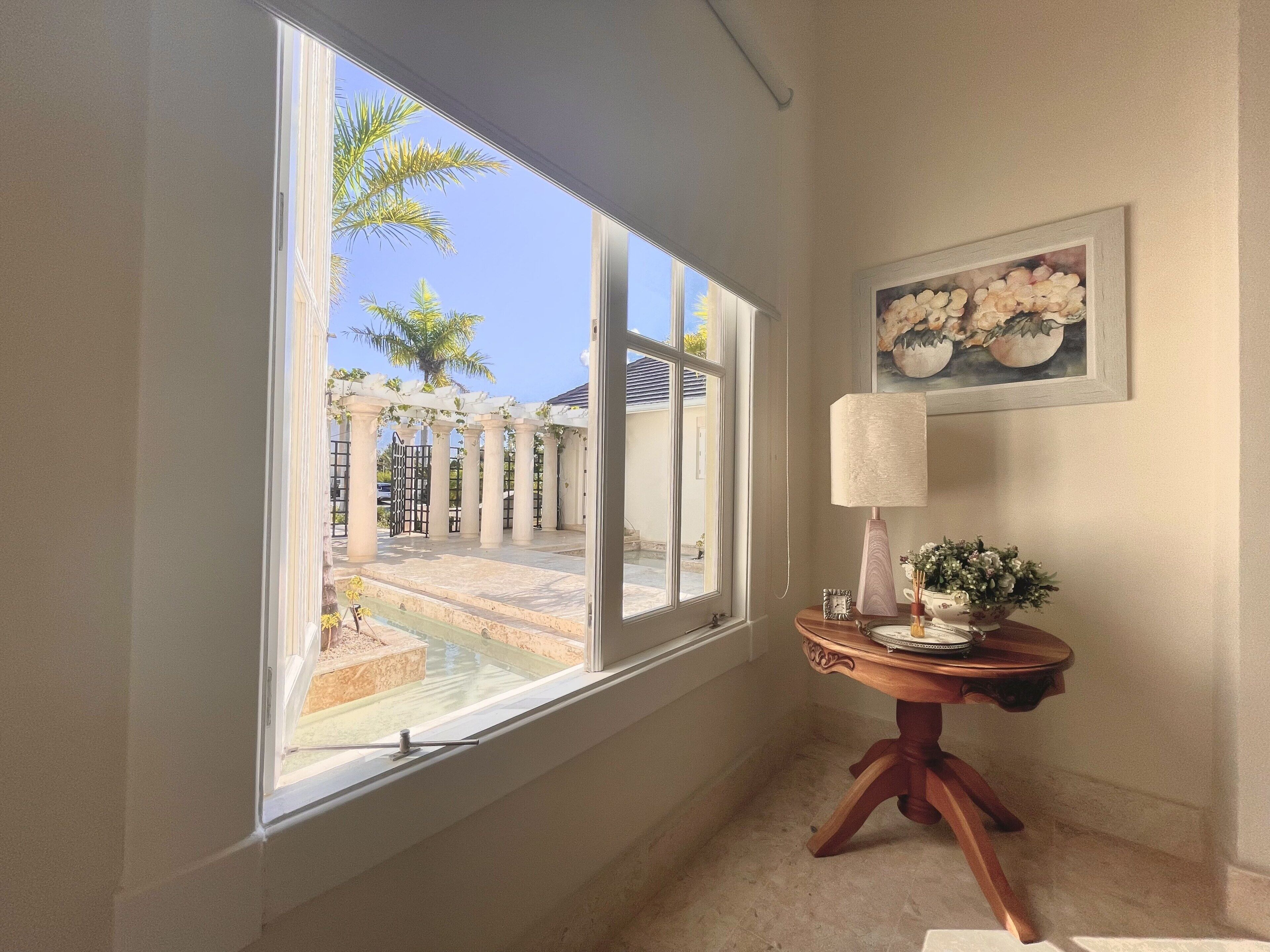 An open window with a view of the courtyard, and a round table with a lamp.