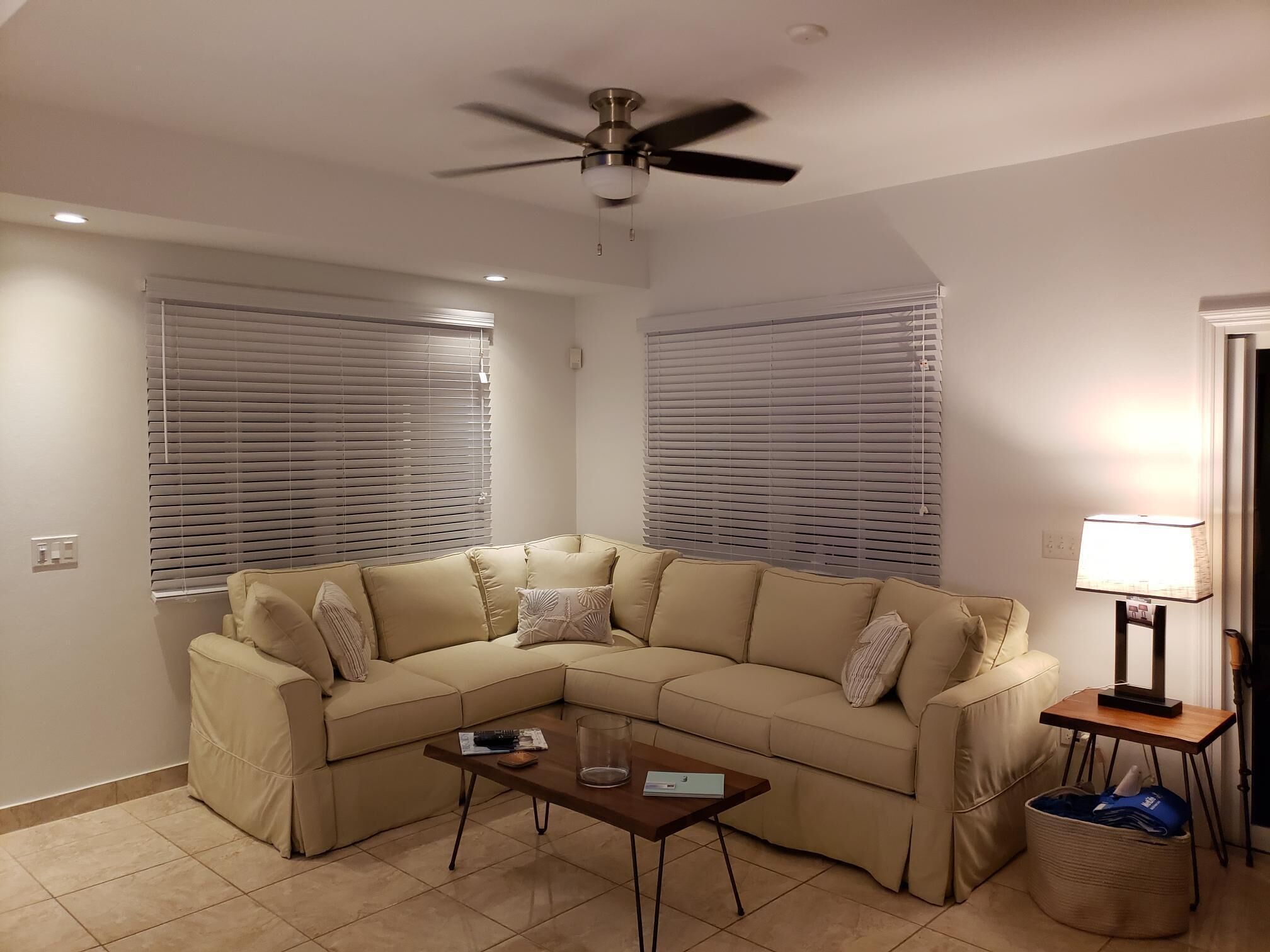 A living room with a beige corner sofa and a ceiling fan.