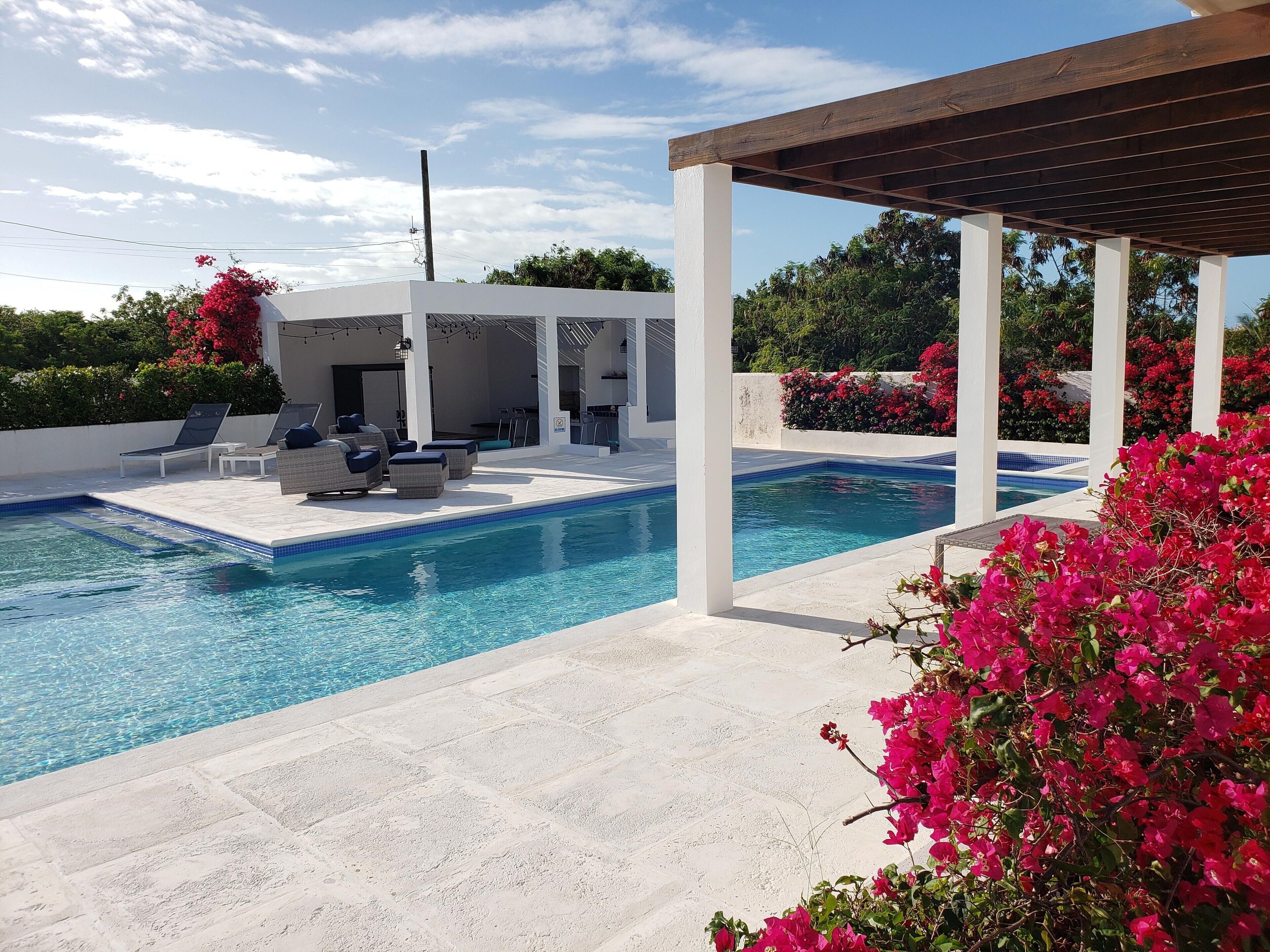 The pool and a pergola with bougainvillea in daylight.