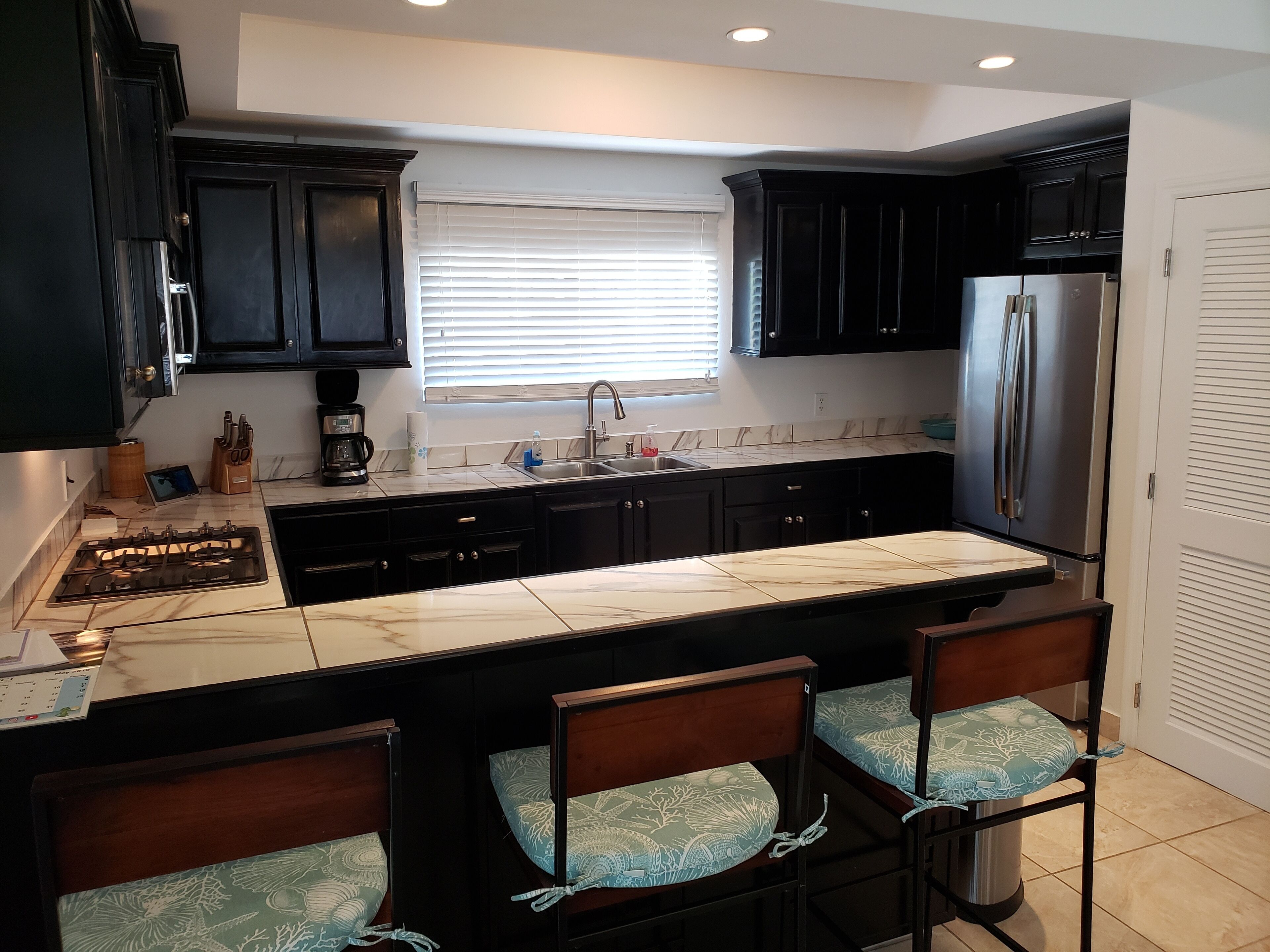 The kitchen with black cabinets and a tiled counter.