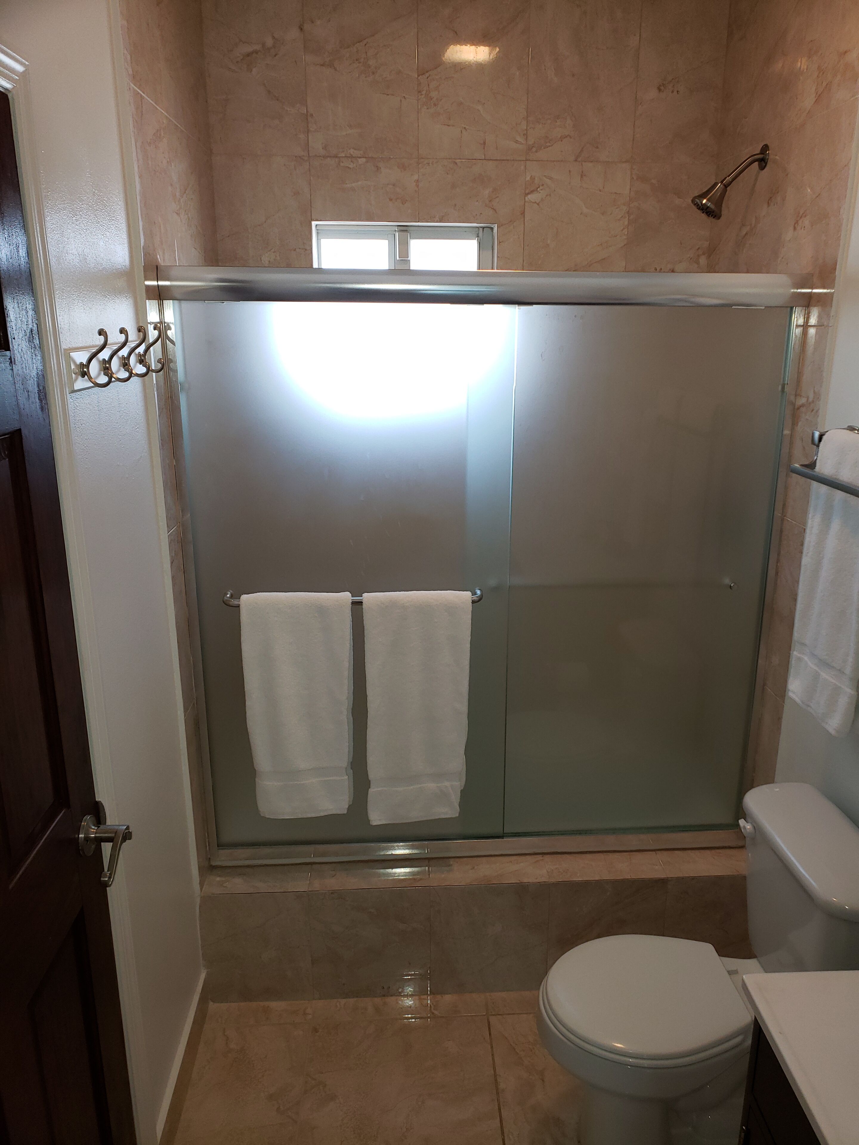 A bathroom with a shower behind frosted glass doors.
