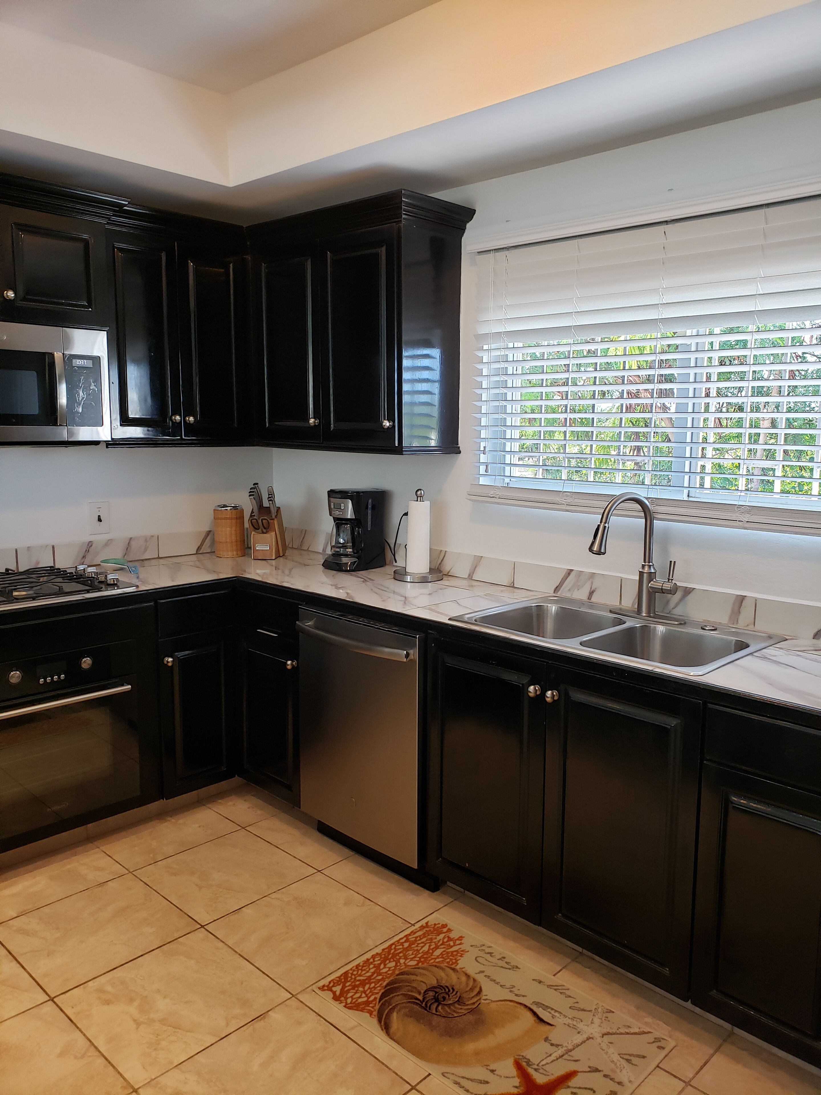 The kitchen sink below a window with blinds.