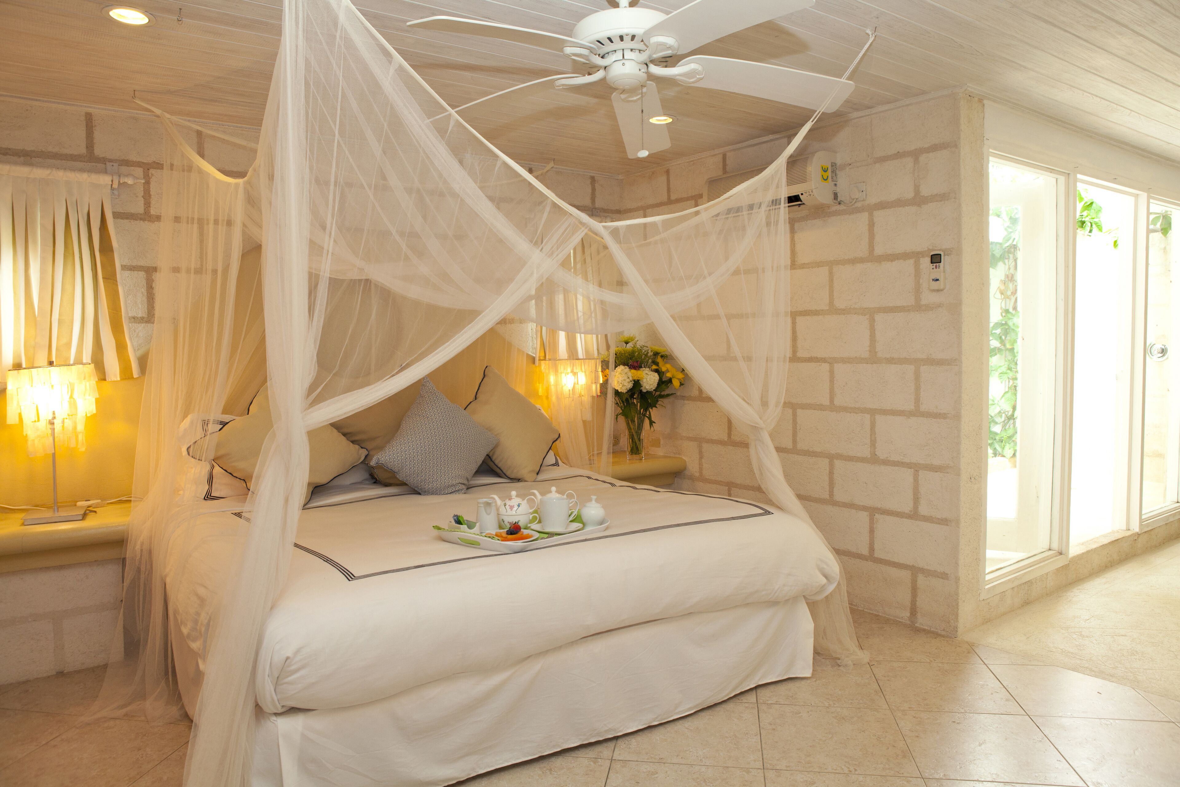 A bedroom with a net canopy over the bed and a breakfast tray.
