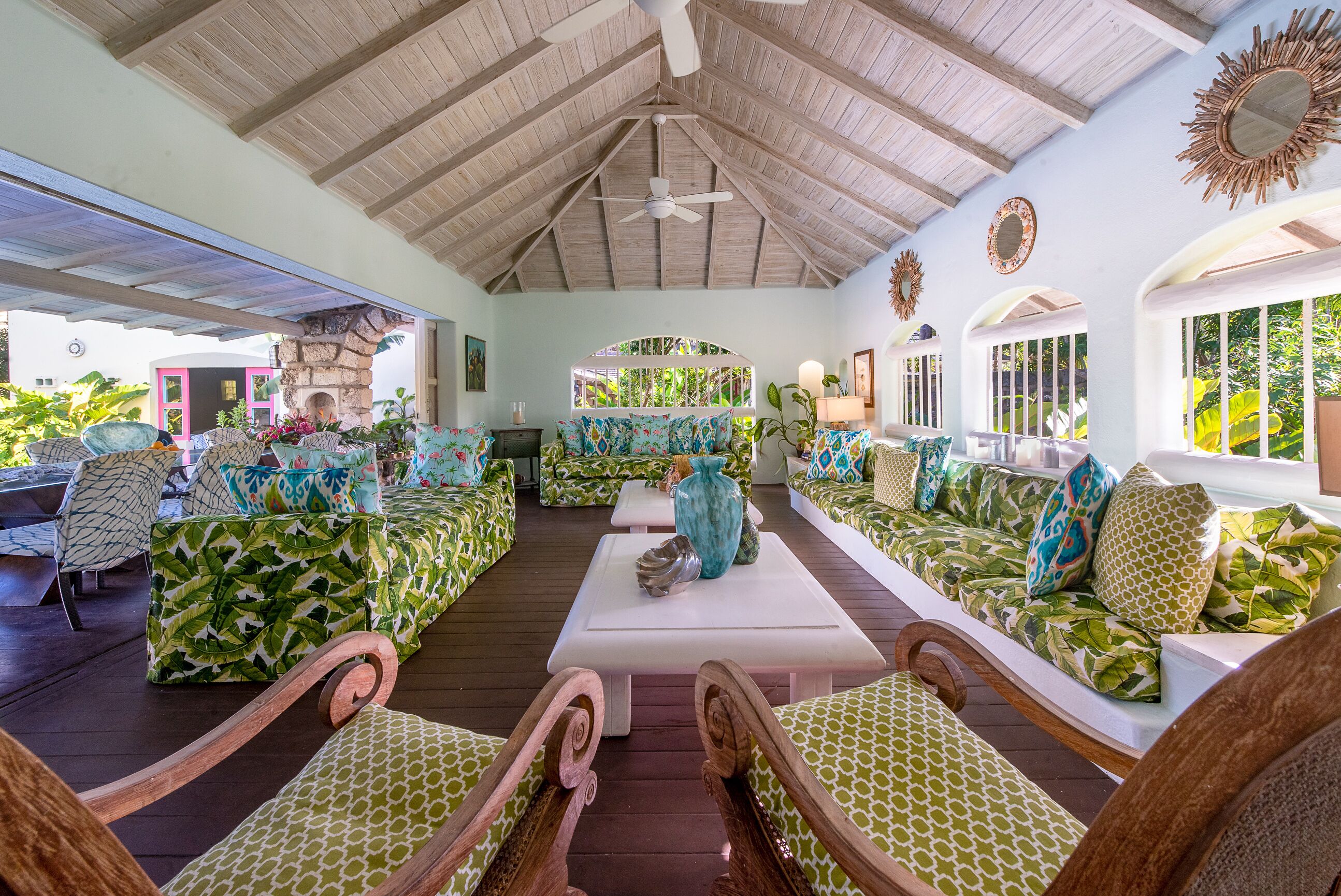 A living room with leaf-print sofas, white tables, and a wood ceiling.