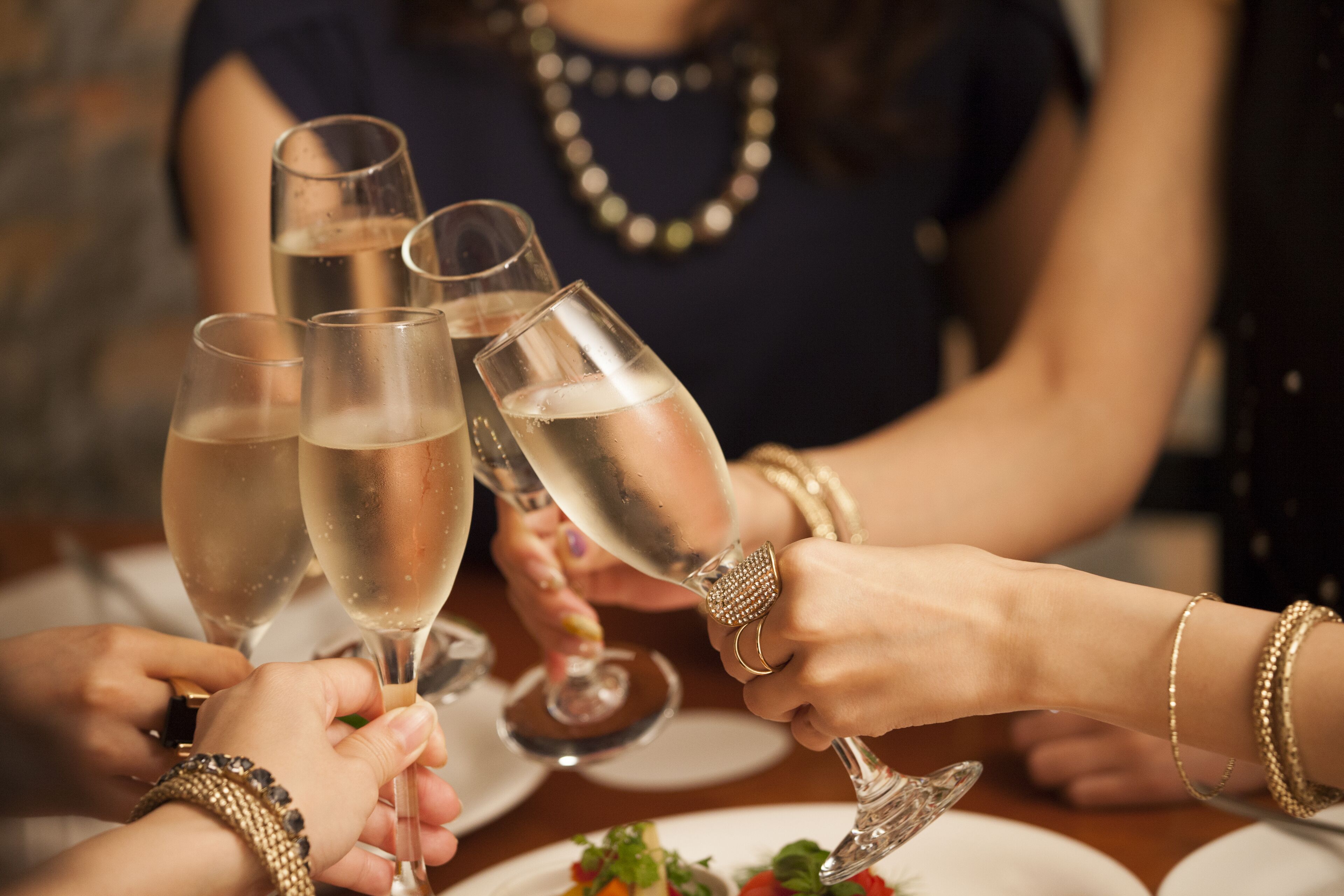 People raise their glasses above a table.