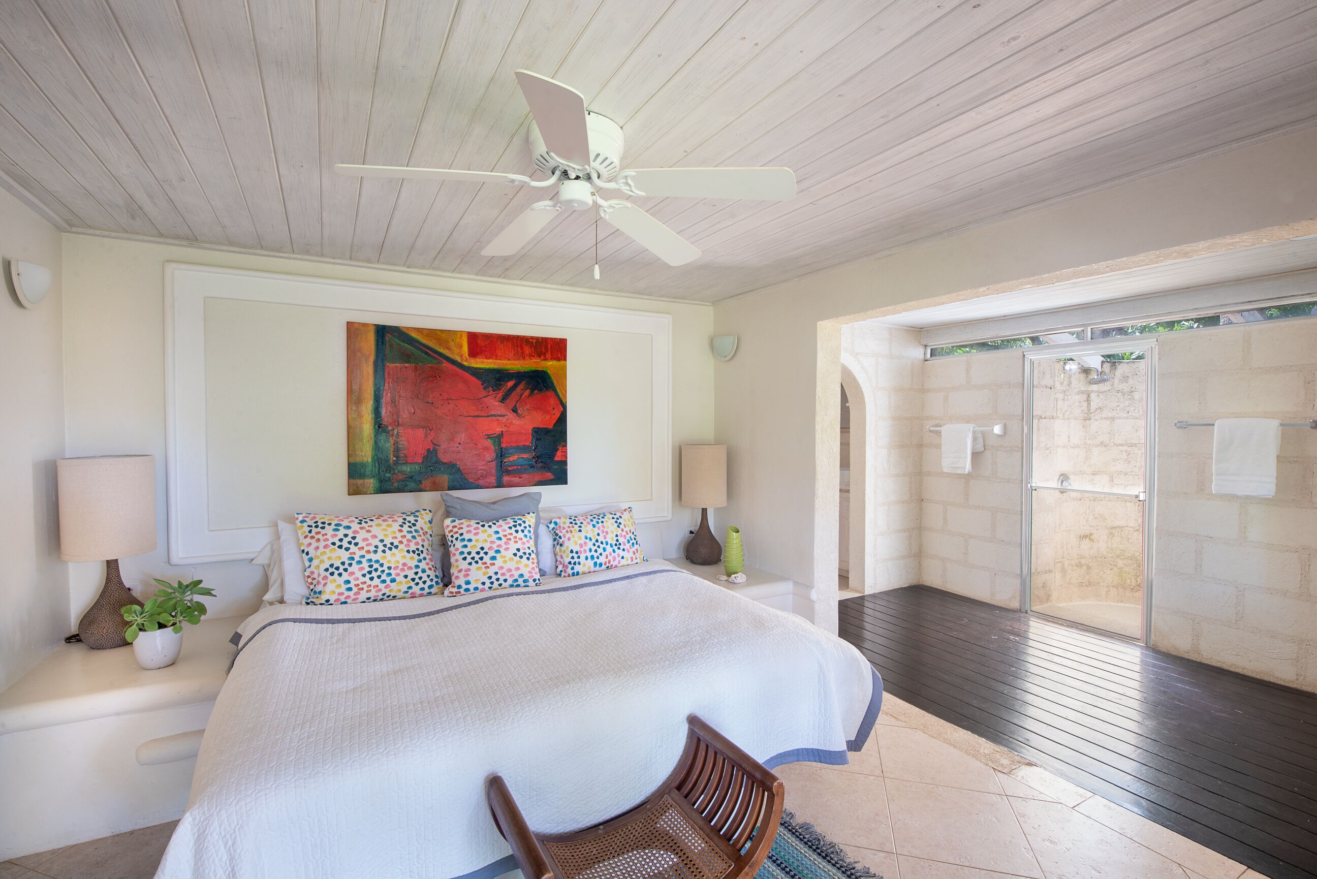 A bedroom with a wall painting and a door to an outdoor shower.