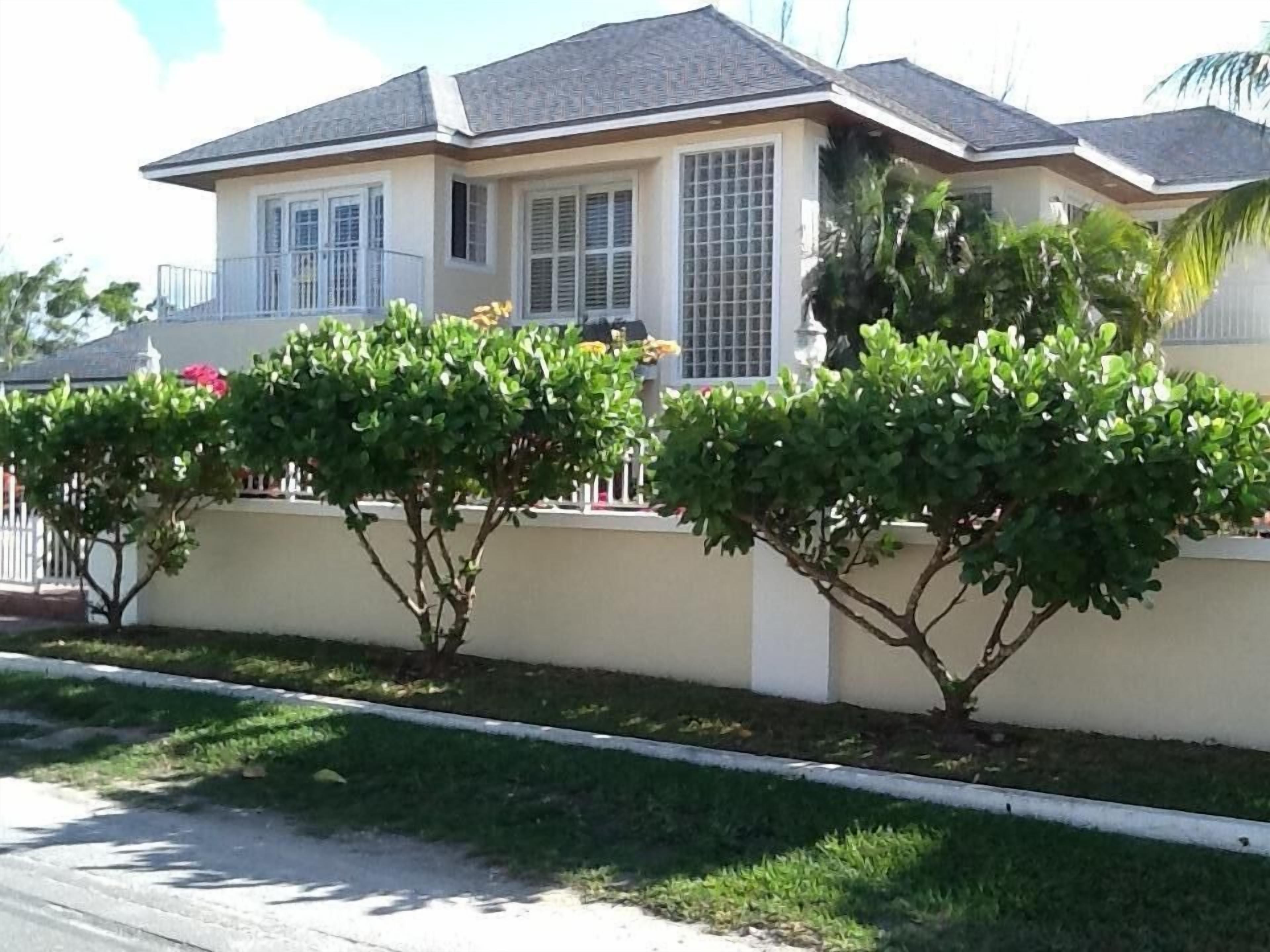 The house behind a garden wall and hedges.