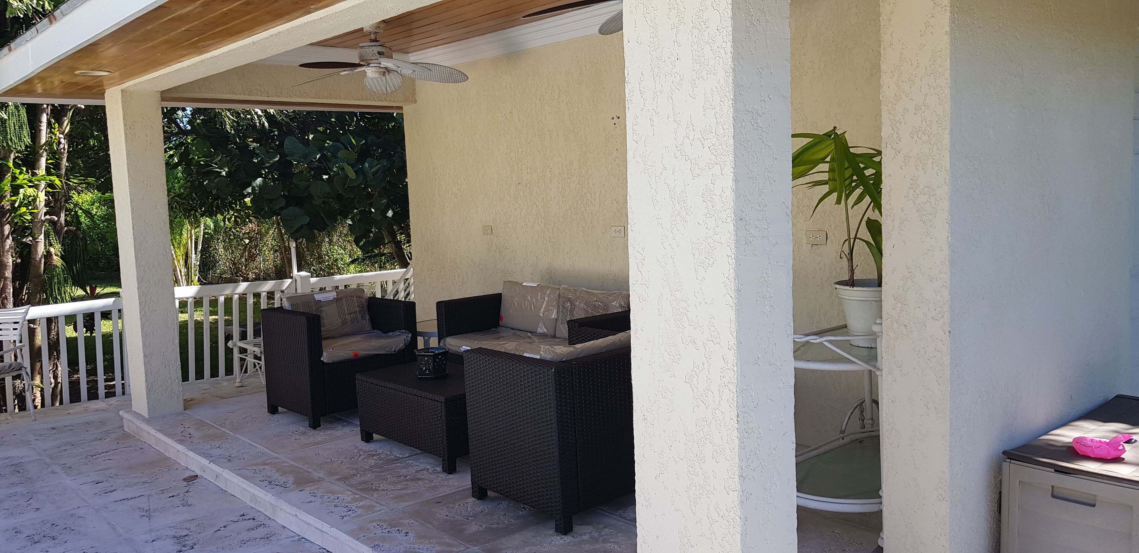 The covered patio with wicker chairs and a table.