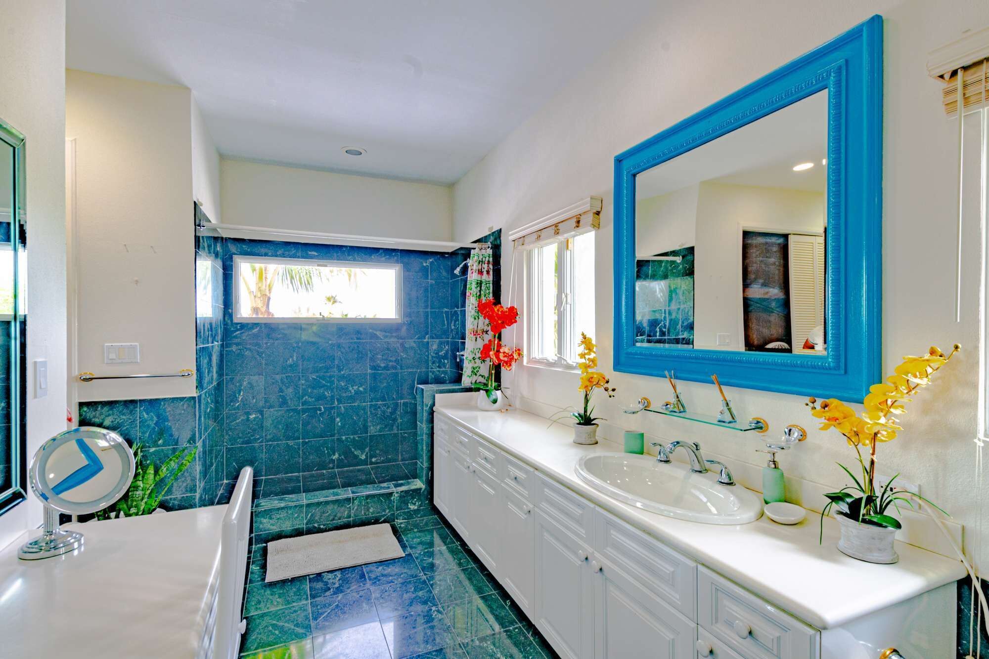 A bathroom with a walk-in shower and a long vanity.
