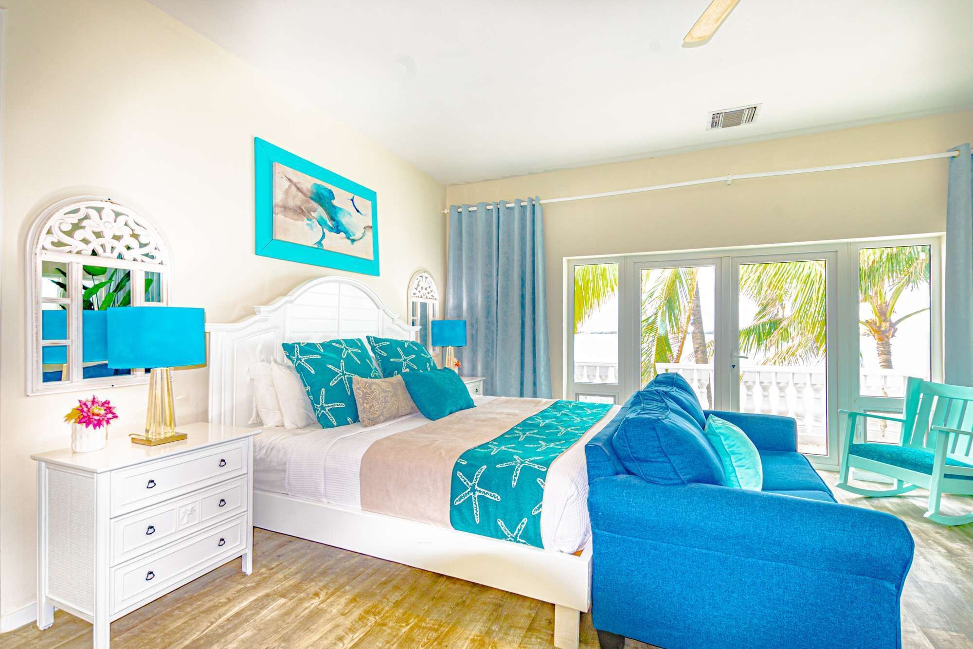 A bedroom with a bed, a blue sofa, and a sea view.