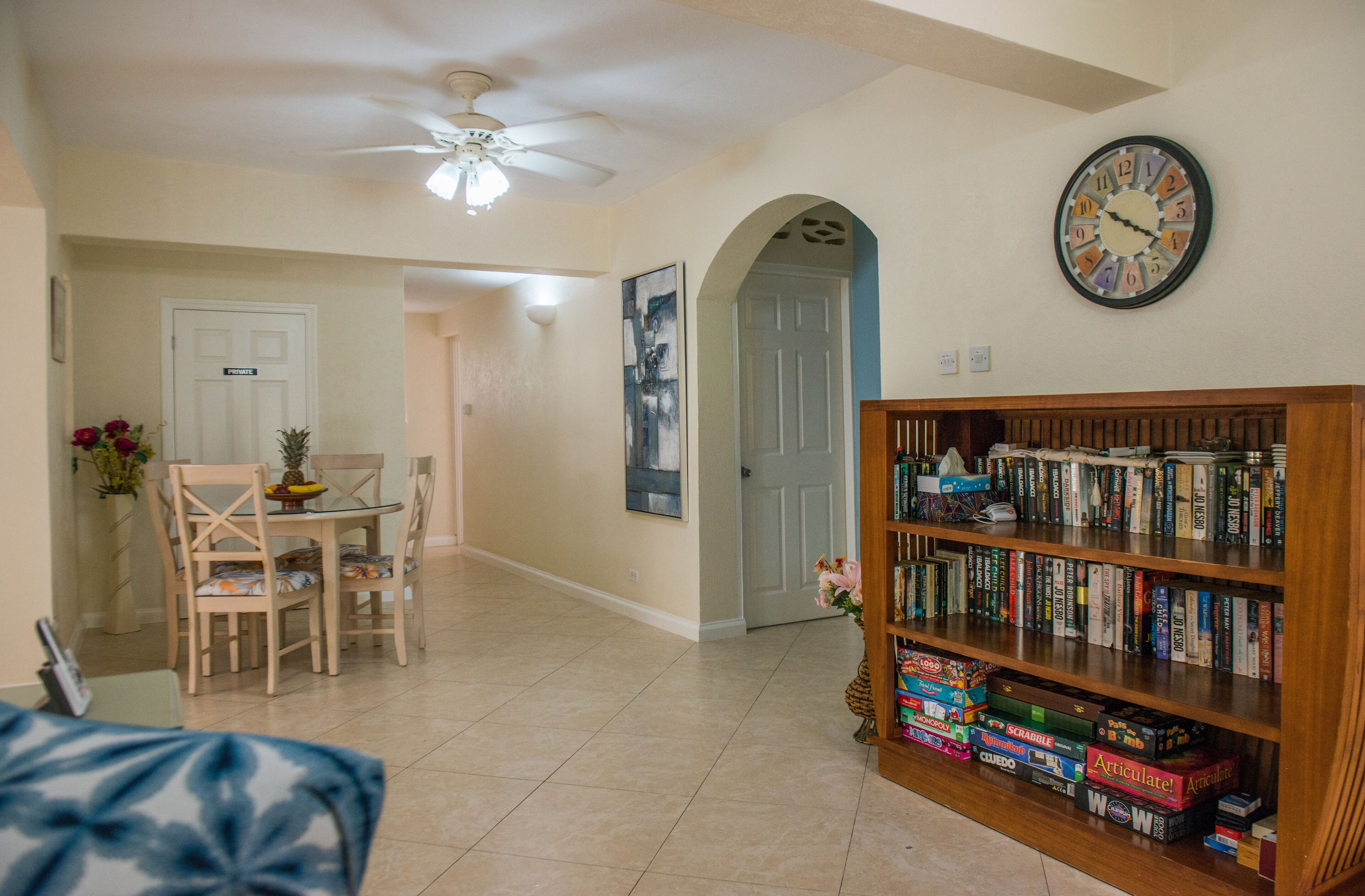 The dining area has a table, four chairs, and a bookcase with books and board games.