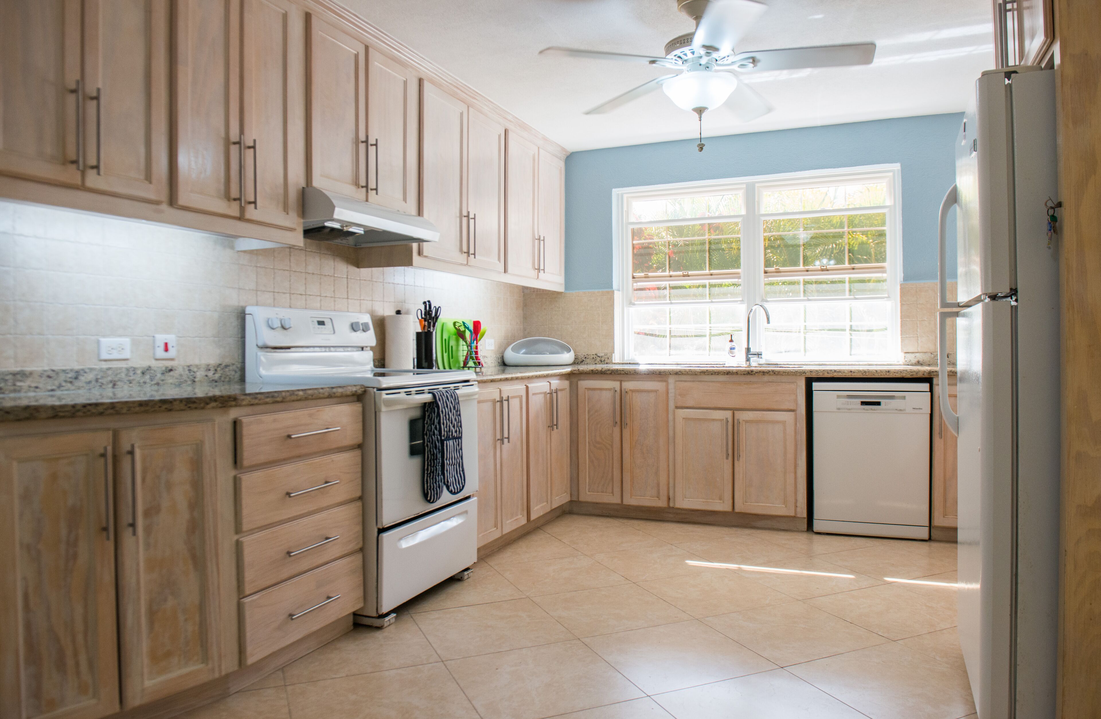 The kitchen has wooden cabinets, an electric stove, a dishwasher, and a refrigerator.