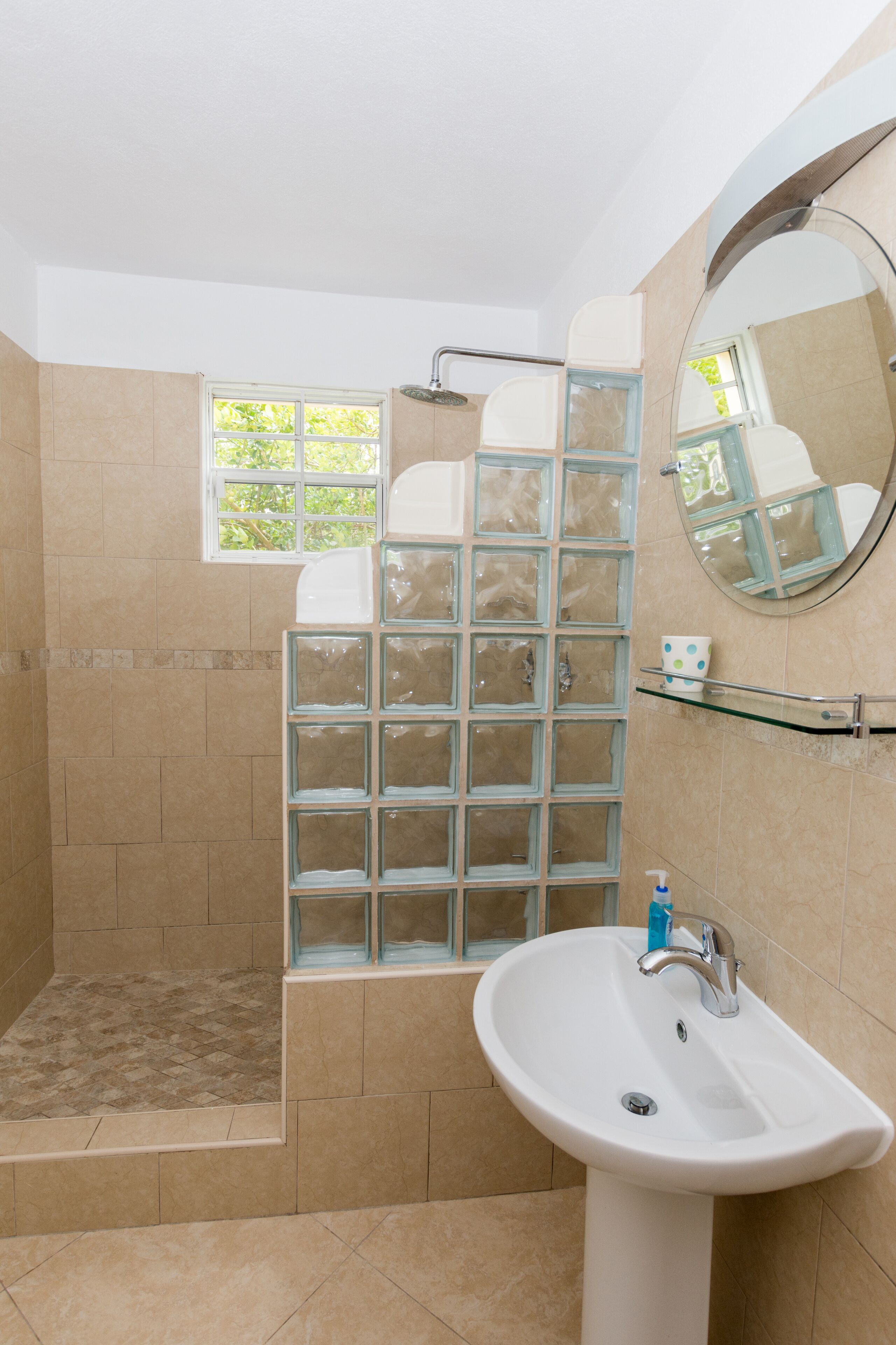 The bathroom has a walk-in shower with a glass-block wall and a pedestal sink.