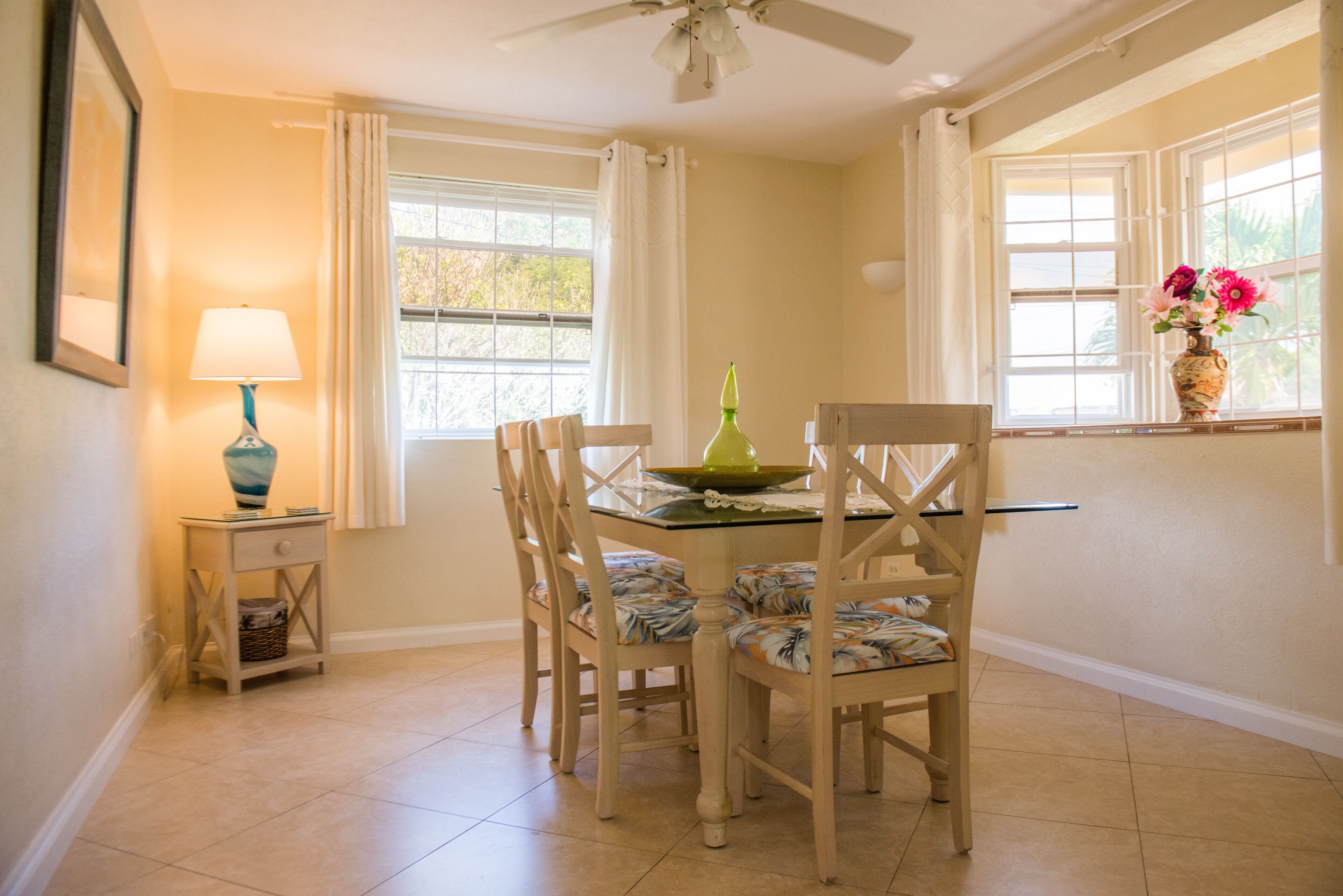The dining room has a glass table and four chairs with cushions.