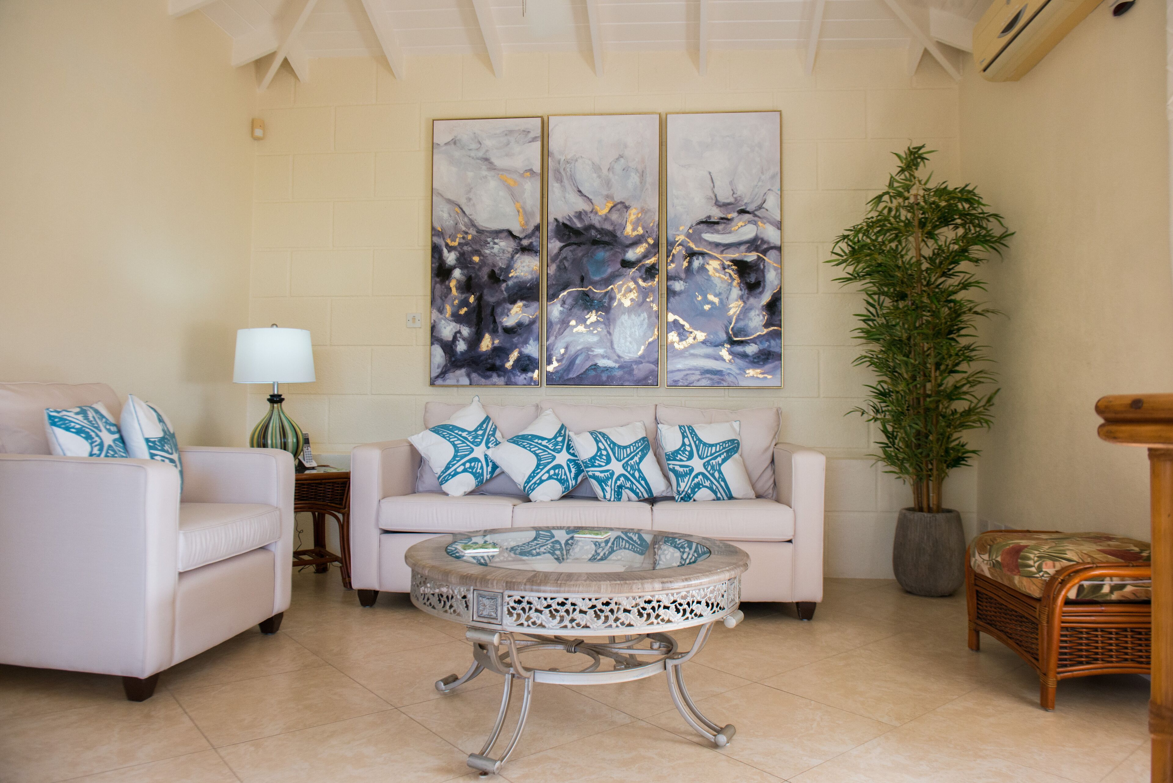 The living room has two cream sofas, a coffee table, and wall art.